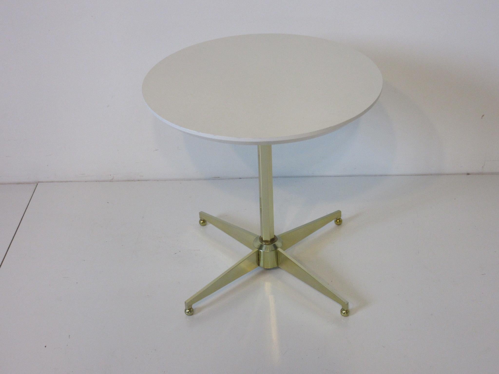 A polished brass star and octagon shaft based side or end table with a round white laminate top and small brass balls as feet, manufactured by the Plametron Company, Miami, Fla. A very simple but elegant design from the period.