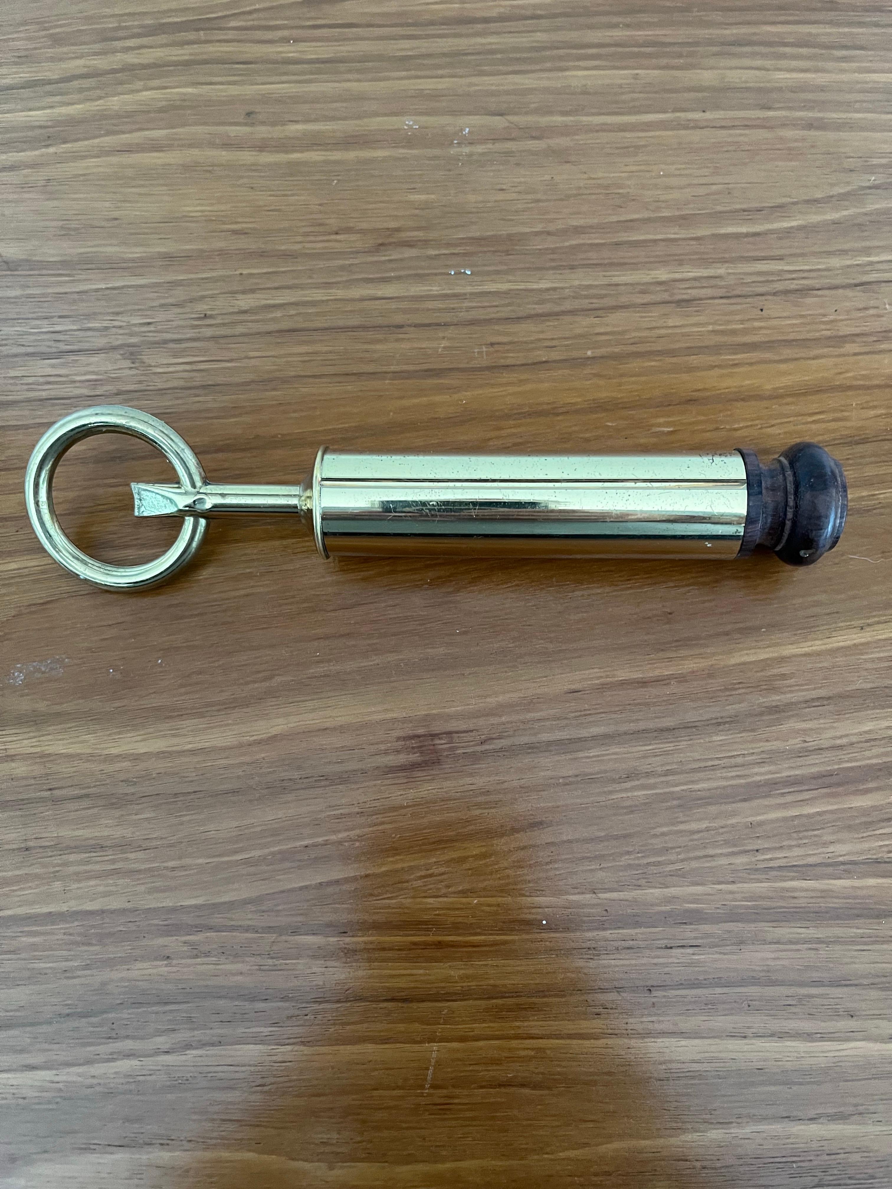 Wonderful mid century brass or gold plated bottle opener attributed to Aldo Tura, Italy. Heavy brass handle adorned with a Grecian Chariot medallion and wooden end cap which appears to be rosewood.