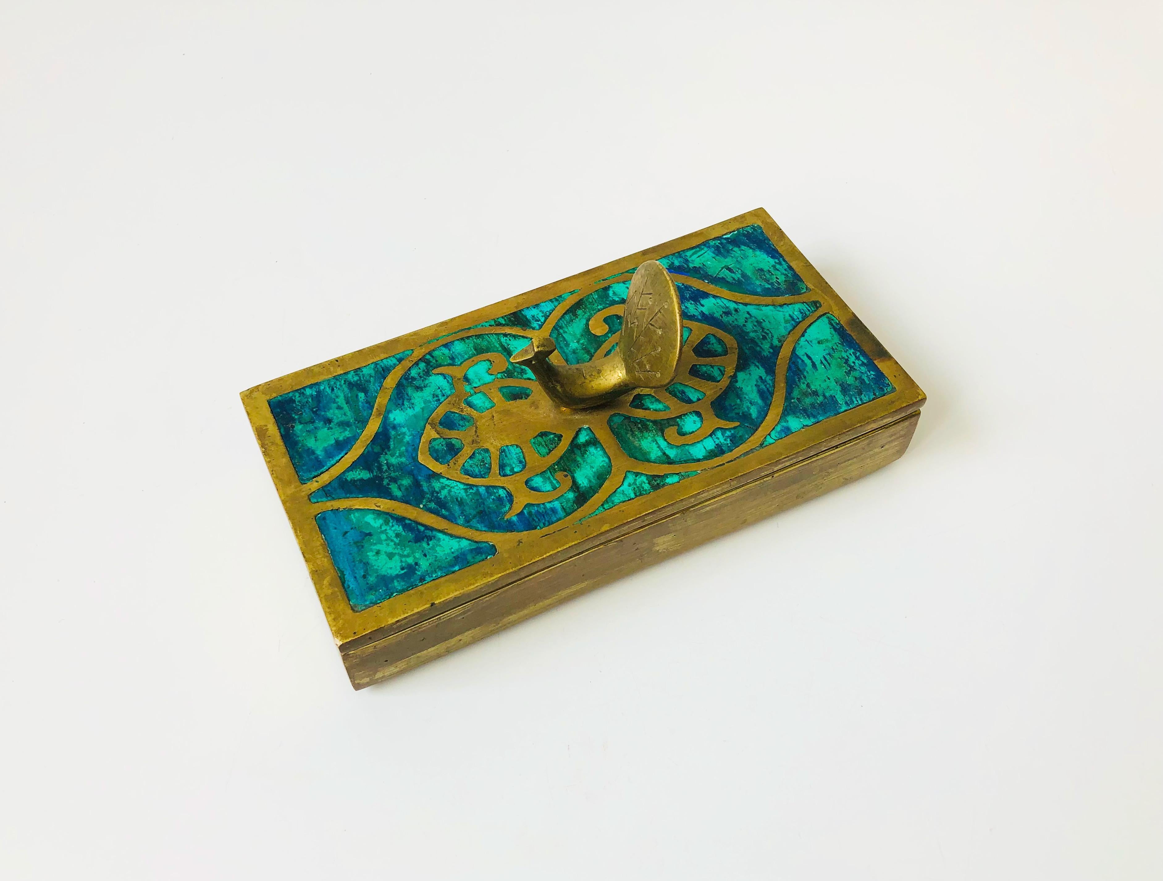 A mid-century rectangular brass box by Mexican designer Pepe Mendoza. Features a beautiful turquoise enamelled design on the lid with a brass peacock handle. Substantial in weight. A rare and unique mid century treasure.
 