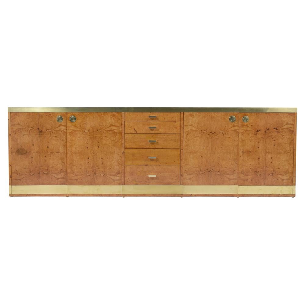 This 1960s mid-century credenza designed in the style of Paul Evans has been newly restored, features its original large brass accents along the top/bottom, is made out of maple wood covered in elegant burled birch wood veneer, and has a newly