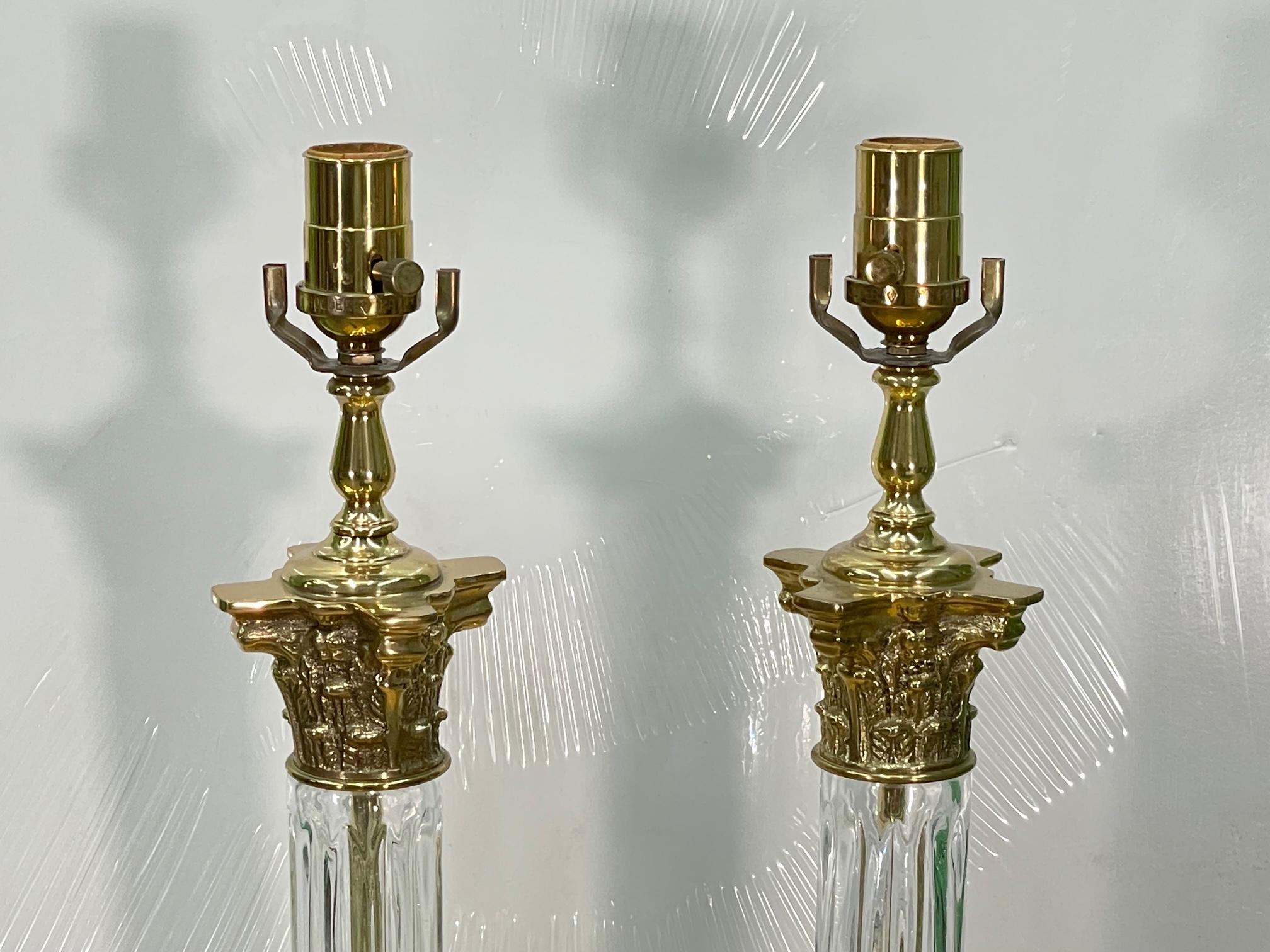 Pair of brass and crystal Roman column table lamps feature Corinthian capitals and fluted crystal shafts. Good condition with minor imperfections consistent with age, see photos for condition details. 
For a shipping quote to your exact zip code,
