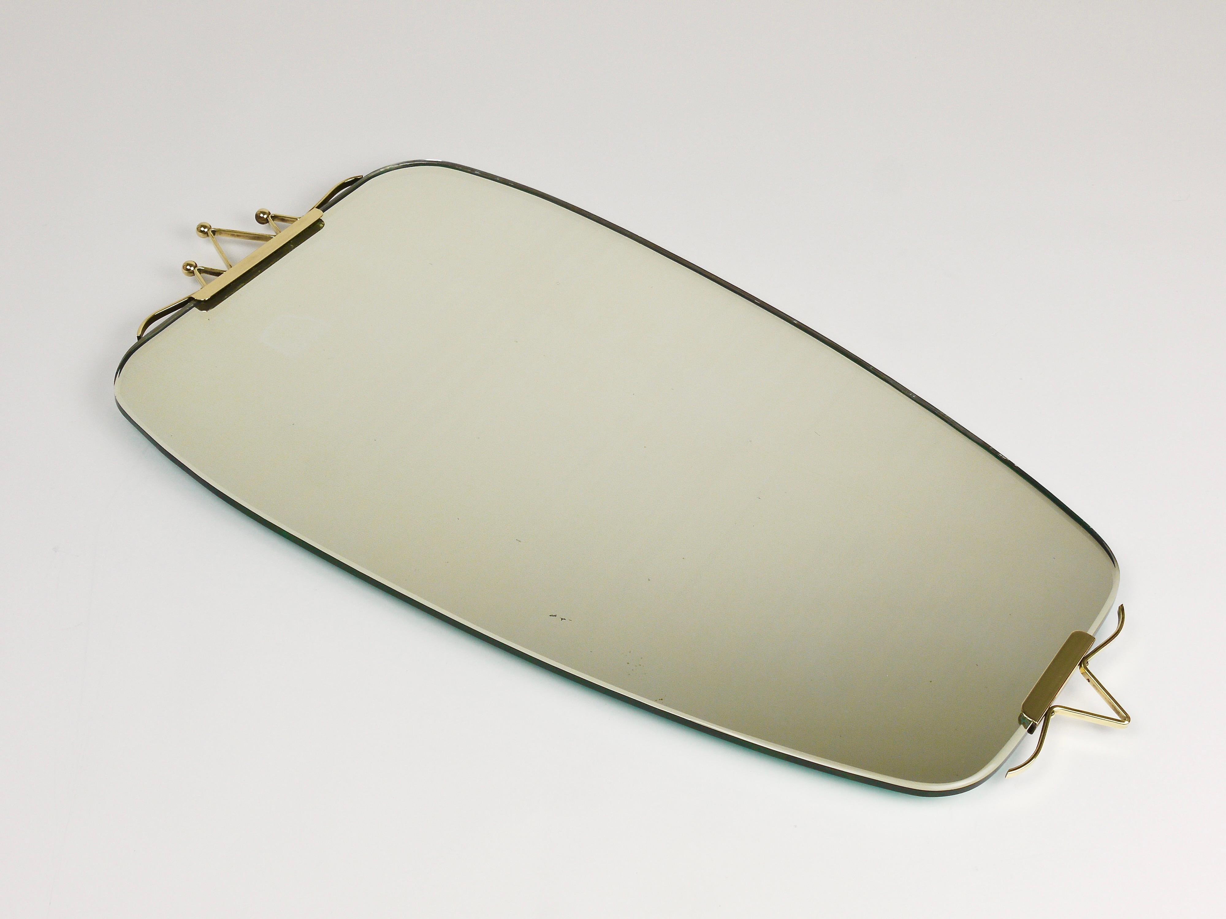 This elegant and beautifully proportioned Italian vintage wall mirror dates from the 1940s. Featuring a subtly tapered rectangular shape with softly rounded edges and corners. Particularly charming are the distinctive brass accents at the top and