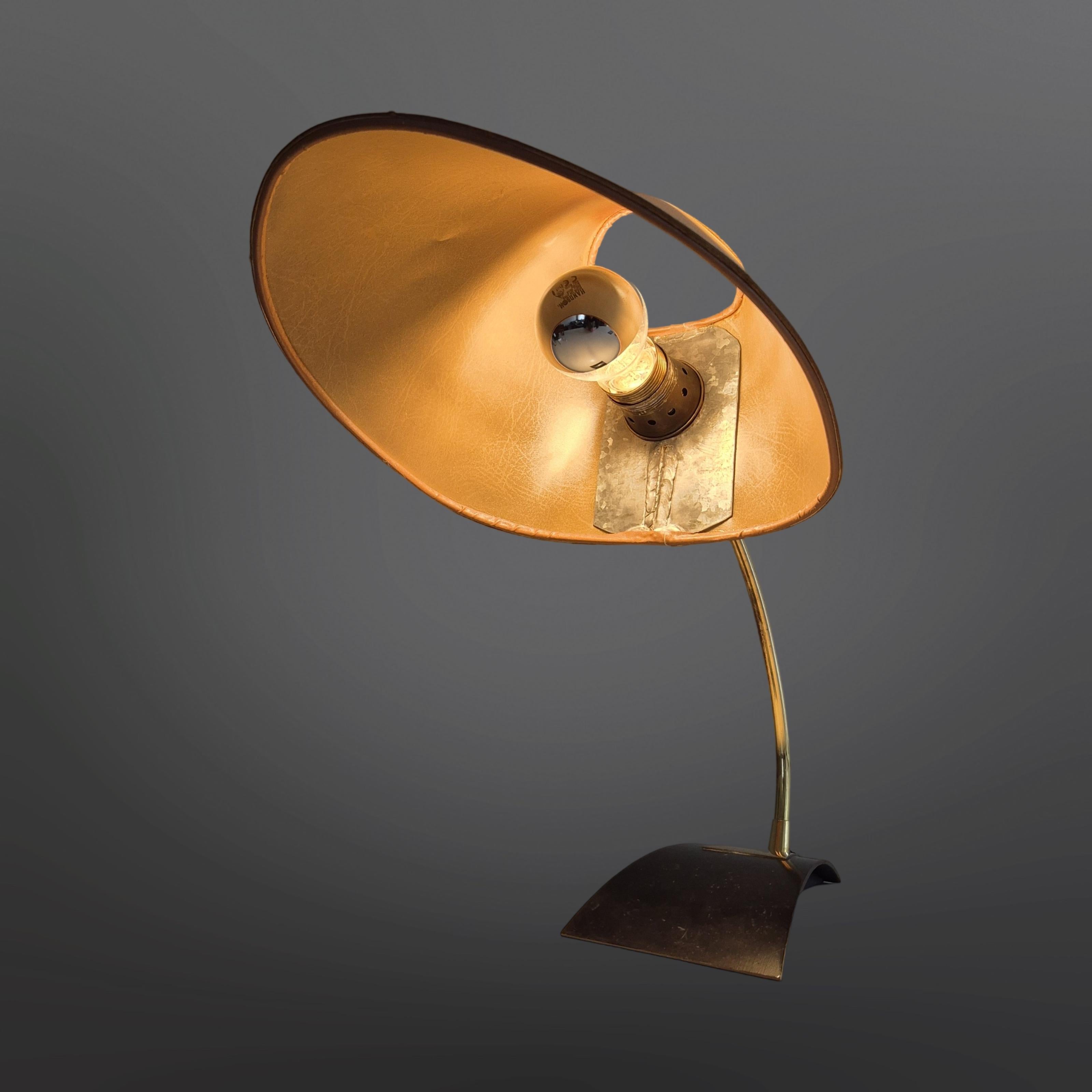 Minimalistische Design-Schreibtischlampe. Hergestellt von der deutschen Firma Kaiser leuchten in den 1950er Jahren. Er hat einen Sockel aus Stahl und Messing. Der Messingarm hält einen pergamentfarbenen Schirm.
Die Lampe ist in gutem und voll