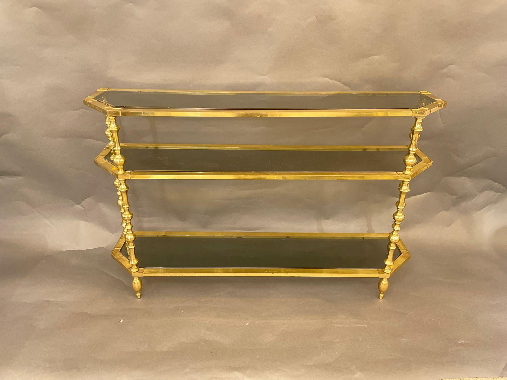 A vintage Italian tiered brass console/étagère from the mid-20th century, with smoked glass shelves. This stylish étagère features an elegant brass structure with three levels of smoked glass shelves.