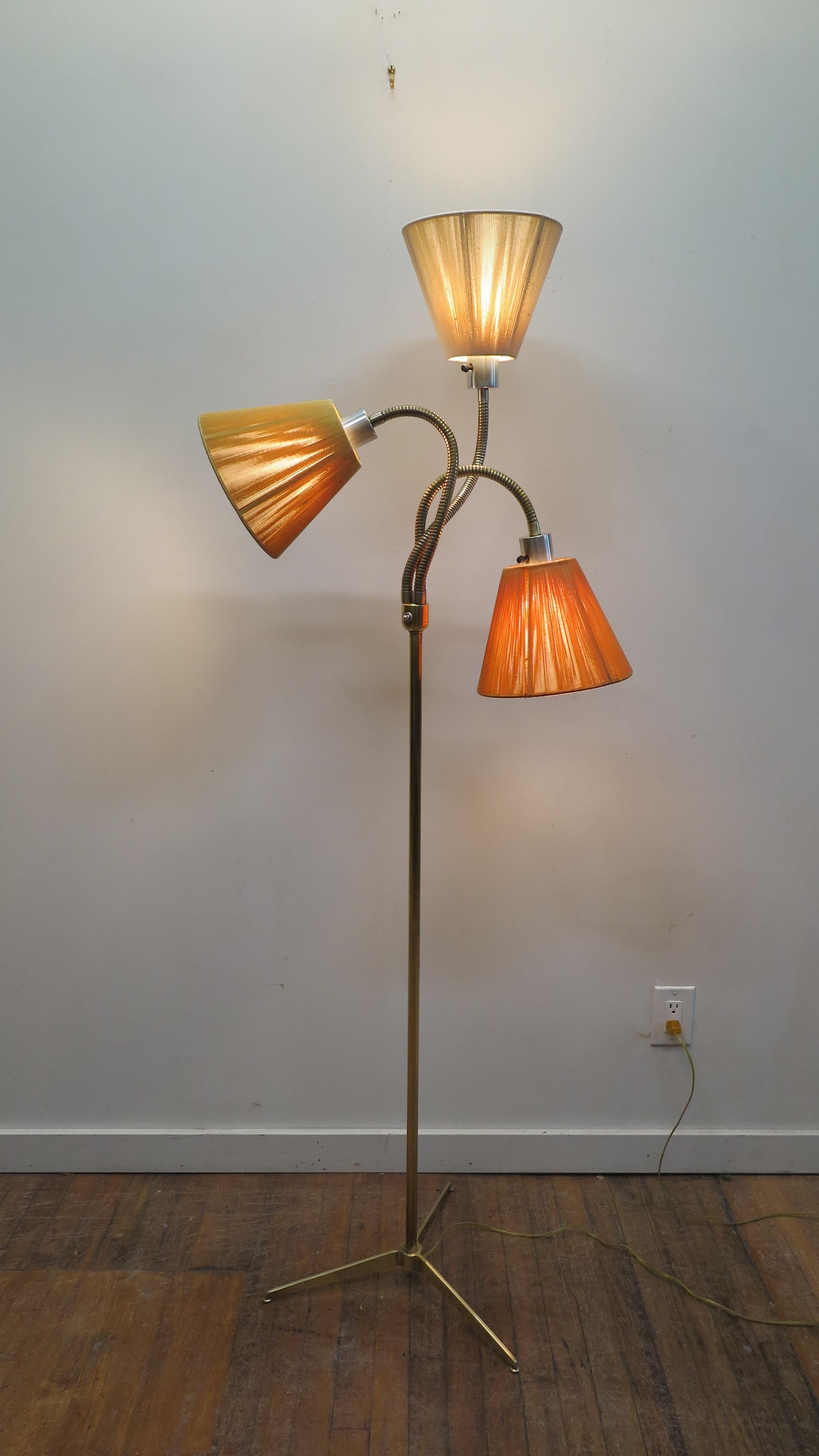 American midcentury brass floor lamp Triennale attributed to Gerald Thurston Lightoleir.  Modernist brass floor lamp on tripod brass legs, brass pole showcasing three goose neck fixtures with original string wrapped shades. Shades are faded showing