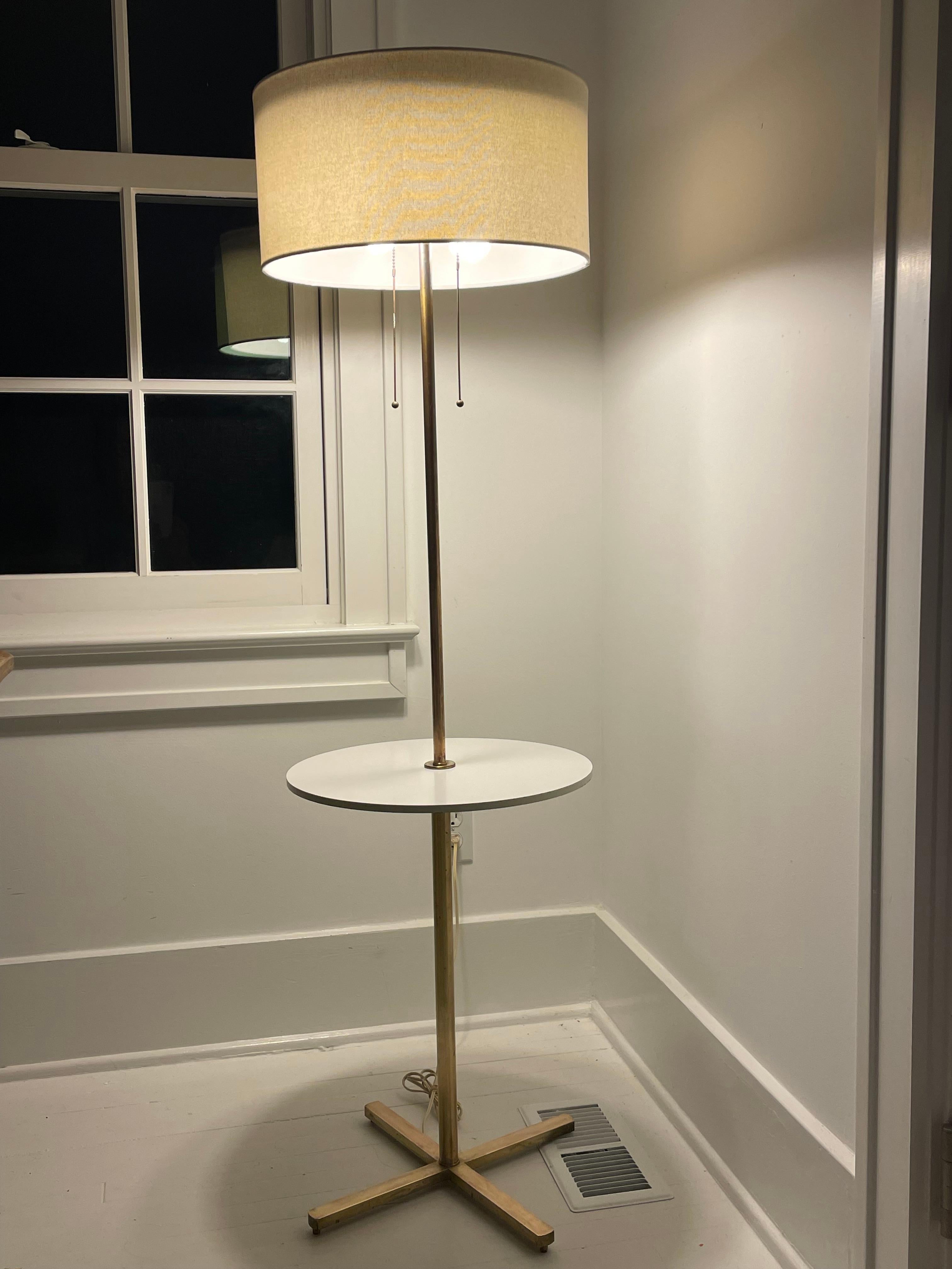 Mid century brass floor lamp with built in white laminate side table . The lamp has two sockets with lovely thin brass pulls. Each bulb works independently.. The shade has a diffuser . Unmarked .Solid and well made . 