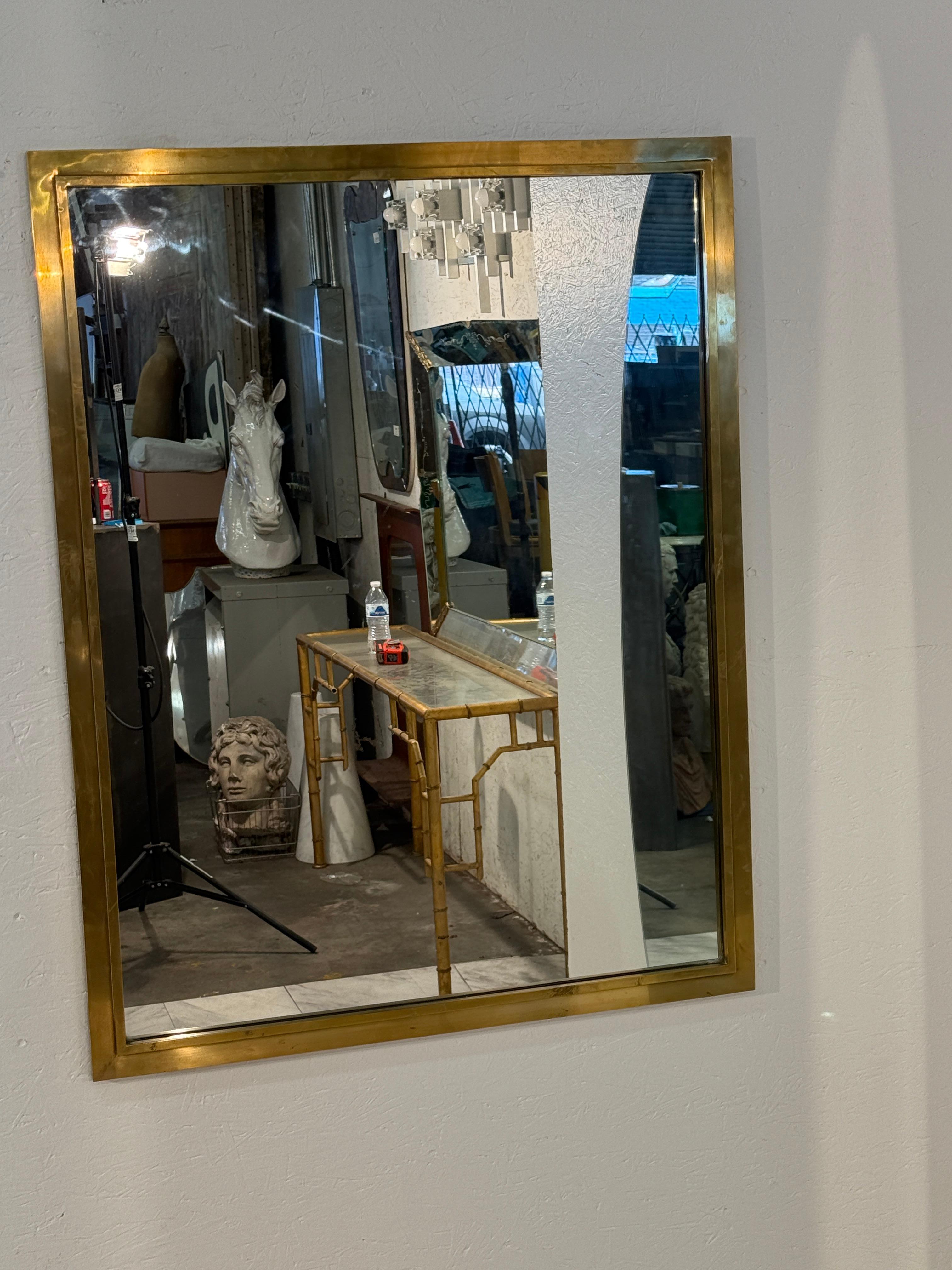 Un miroir mural italien rectangulaire et épuré, enchâssé dans un large cadre en laiton, offrant à la fois force et élégance. Le ton chaud et doré du laiton contraste magnifiquement avec le verre réfléchissant, créant une pièce à la fois intemporelle