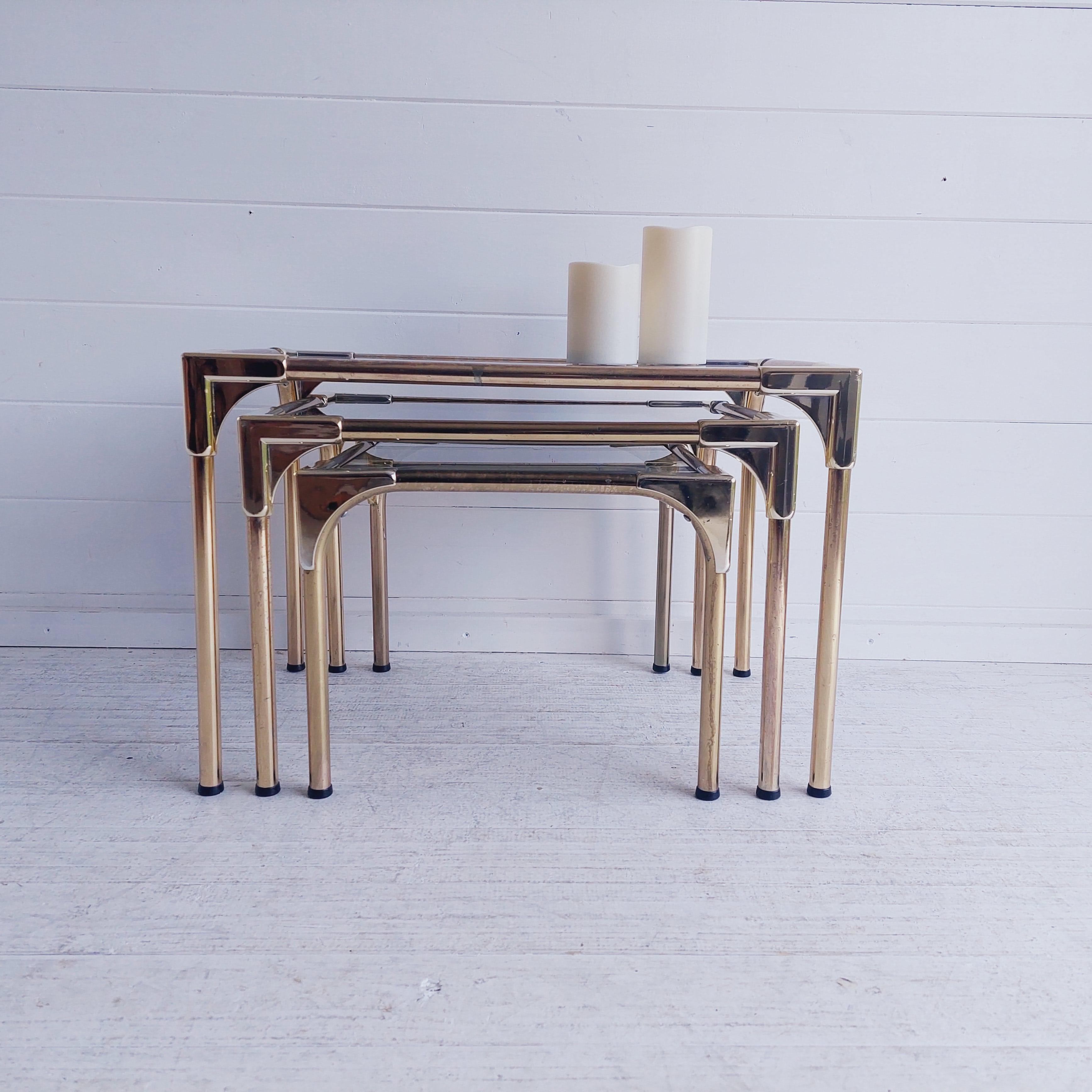 Stylish mid-century modern nesting tables from the 1970s. 
Original circa 1960/70’s Mid-Century Modern French Empire brass and smoked glass tables

Made of gilted aluminum with brass effect with smoked glass and gold plastic joints.
Perfect for