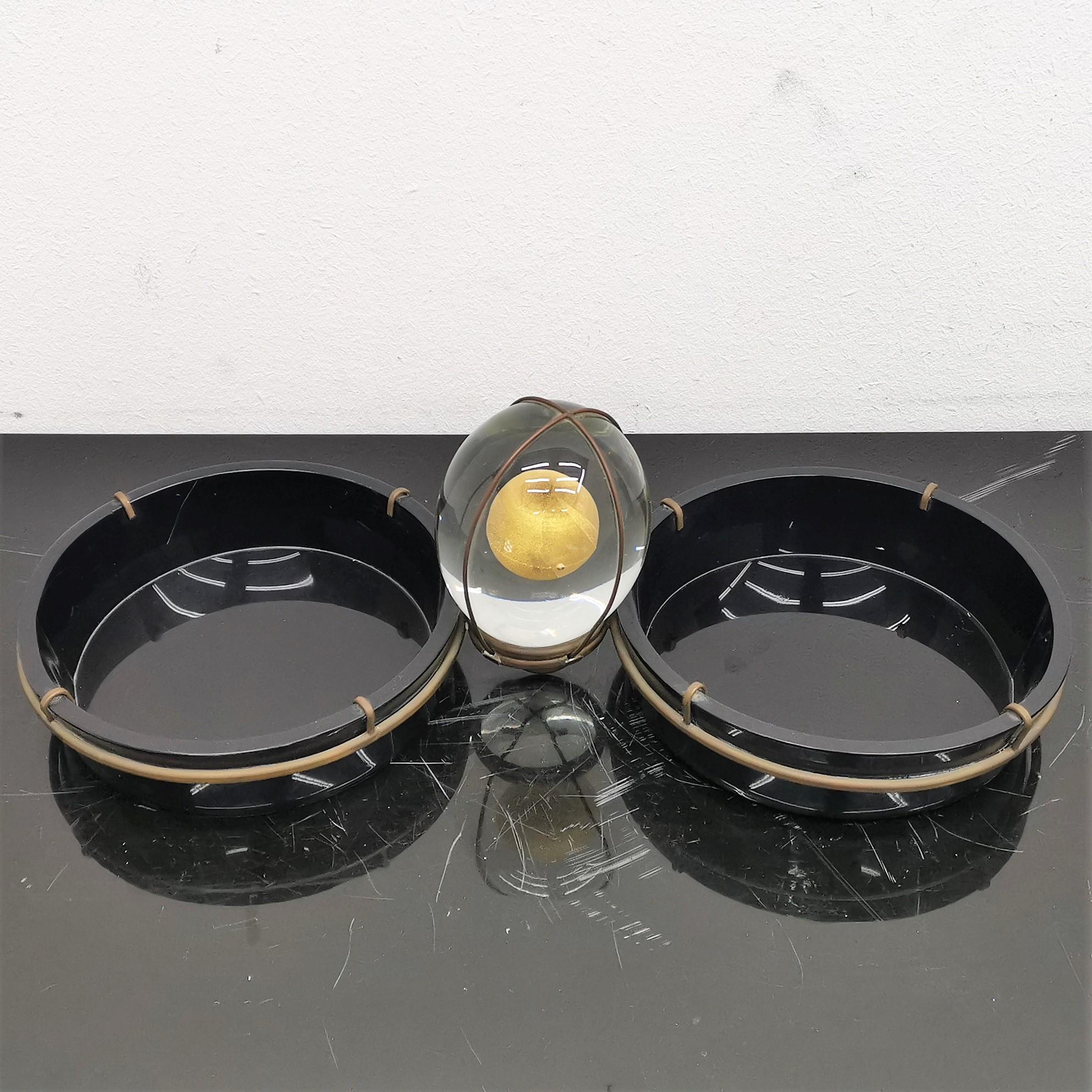 Very beautiful Tommaso Barbi empty pocket, with two circular containers in black plastic at the sides of a glass spheroid with a gold leaf sphere inside. All the shapes are joined together by brass structure, 70s, Italy.
Wear consistent with age