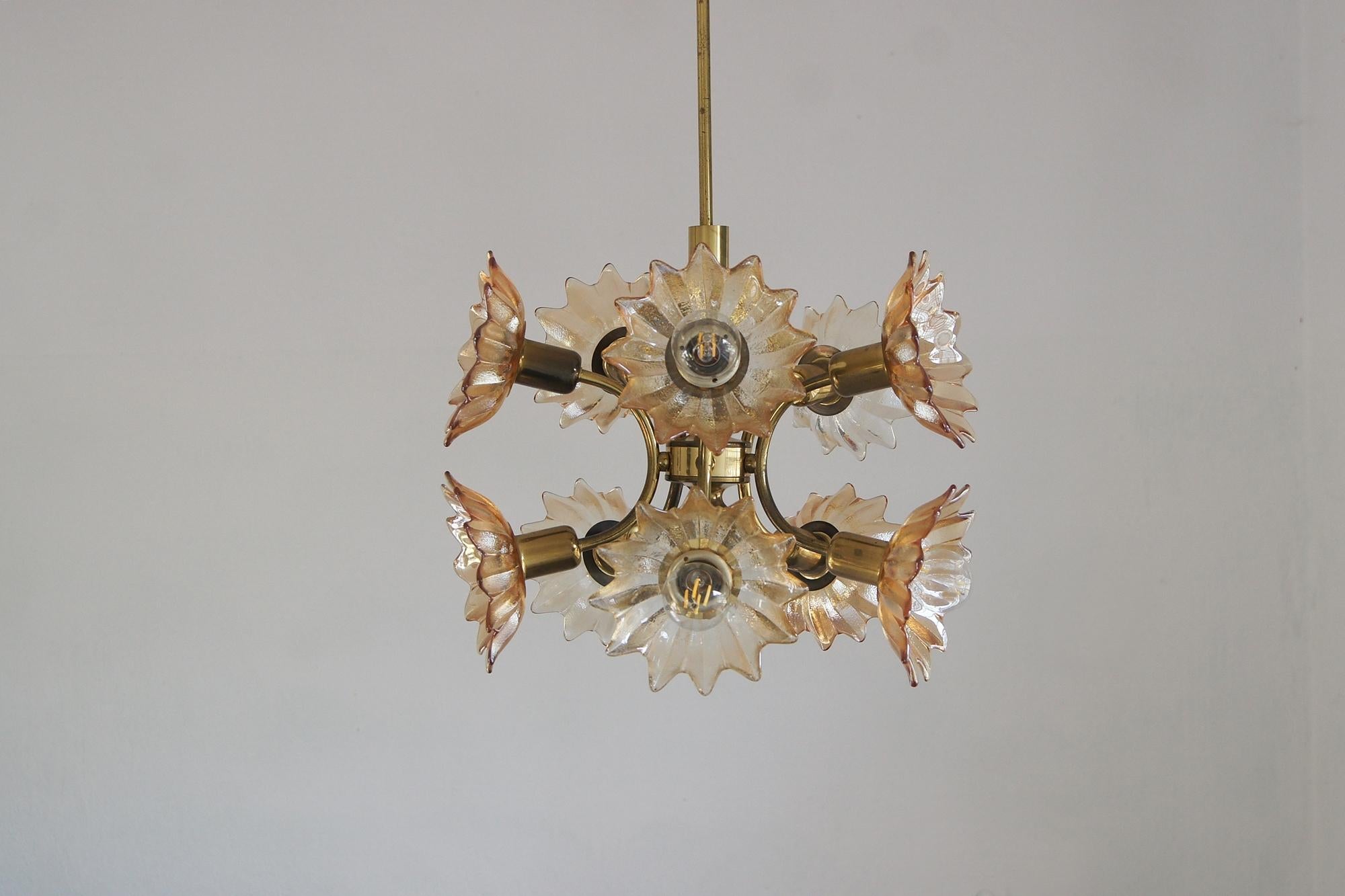 Un lampadario unico dell'azienda tedesca Sische Lighting, nota per il suo design artistico e la sua maestria artigianale. La struttura è realizzata in ottone lucidato e laccato, la cui calda lucentezza dorata si integra armoniosamente con i paralumi