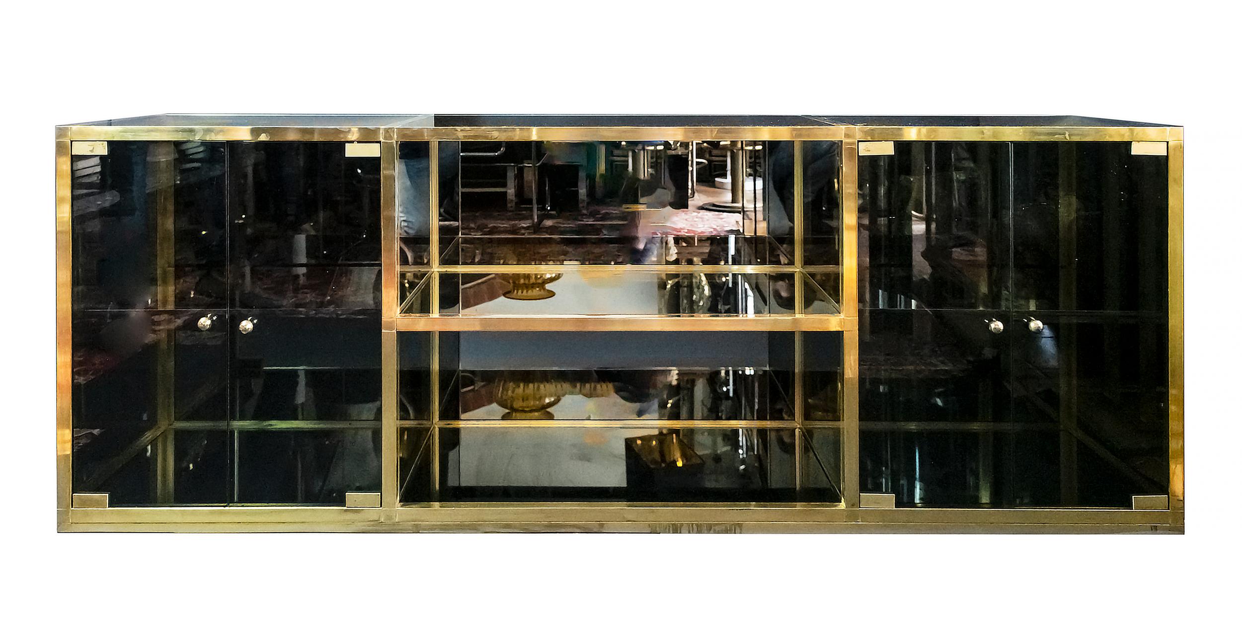 Credenza italiana di metà secolo in ottone e vetro fumé nello stile di Maison Jansen / Romeo Rega degli anni '70.
La struttura in ottone massiccio con vetro fumé sui lati, sul piano, sui ripiani e sulle ante. 
Il retro interno è rifinito a