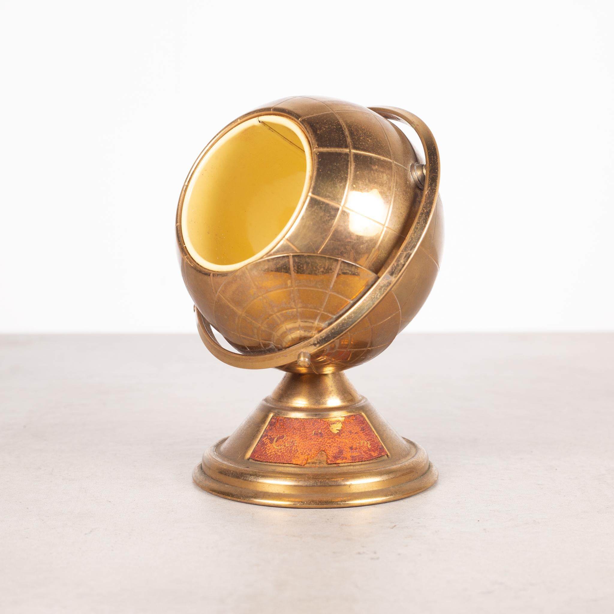 About 

This is an original mid-century brass cigarette holder. The lid slides open on the globe's axis to reveal a metal interior designed to hold cigarettes. This globe is unique because it has a leather nameplate on the bottom. This piece has
