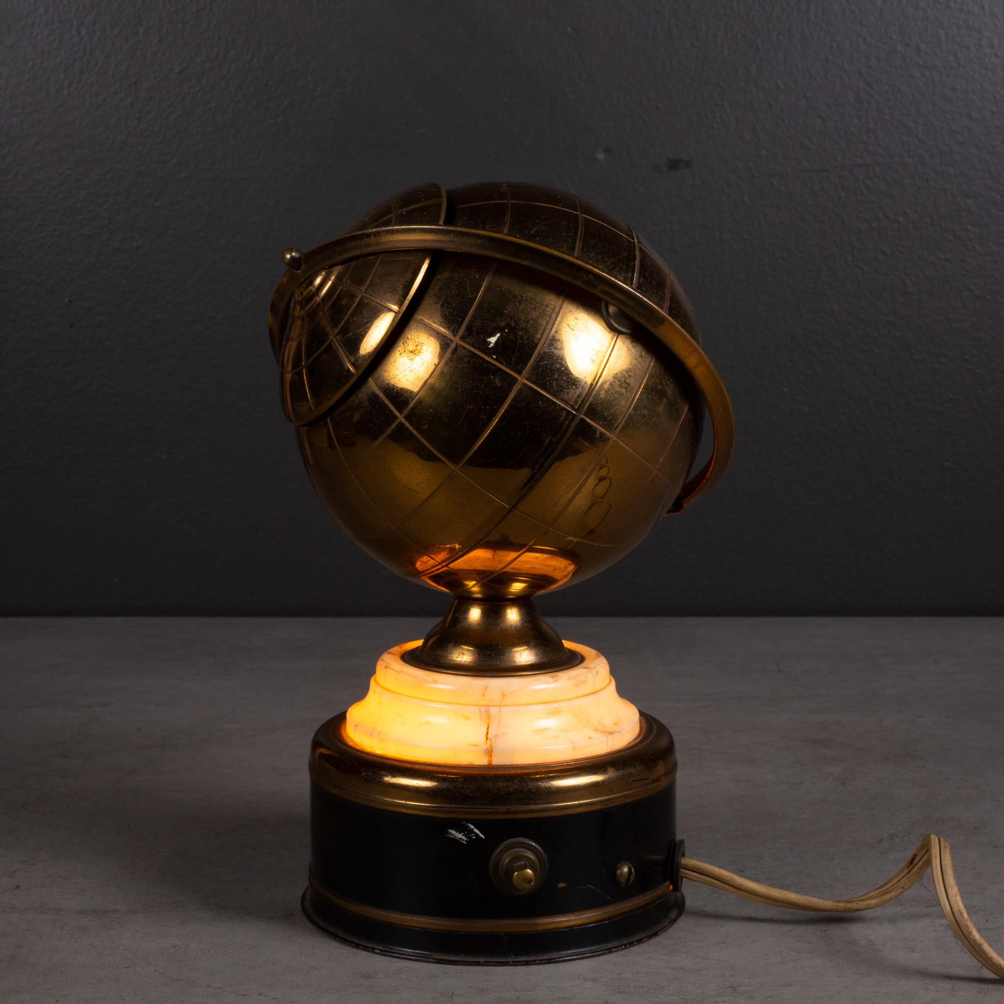 ABOUT 

An original mid-century brass globe cigarette holder with lighted Bakelite and metal base. The lid slides open on the globe's axis to reveal a metal interior designed to hold cigarettes. This piece has retained its original finish and light