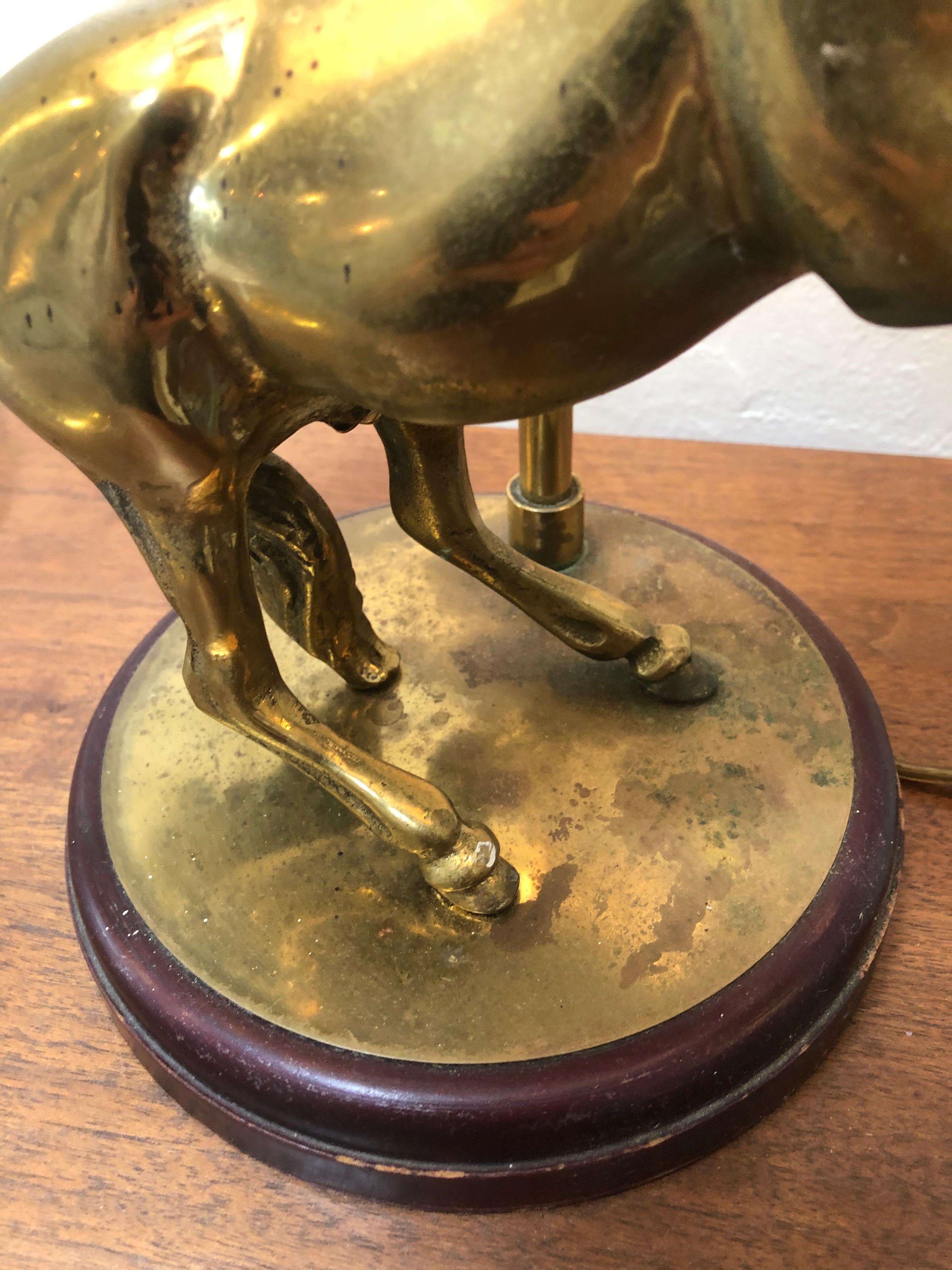 Vintage brass horse lamp fitted with linen lampshade and brass is mounted on wood stand. Lamp also comes with light adjustment switch. Great as an accent piece or desk lamp.