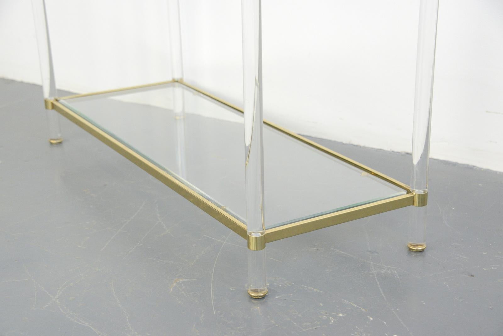 Midcentury brass & Lucite console table

- Lucite legs
- Brass frame
- 2 toughened bevel glass shelves
- French, 1970s
- Measures: 100 cm long x 37 cm deep x 74 cm tall

Condition report:

Some light patina to the brass in places no major
