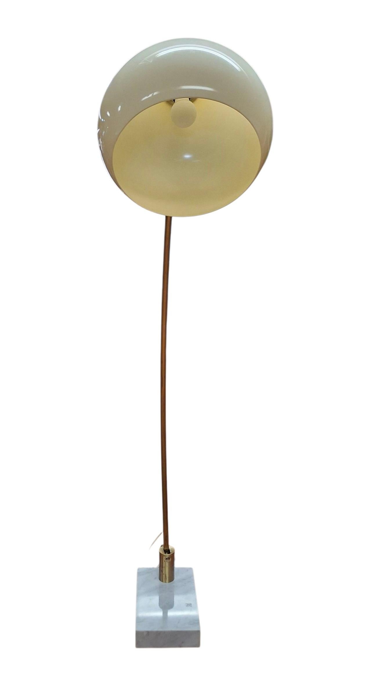 Classic mid-century arc floor lamp with heavy marble base, brass stem with extendable arm, and a cream colored acrylic globe shade.  The base of the stem has a large turn screw to adjust the tilt level and the shade pivots to adjust desired