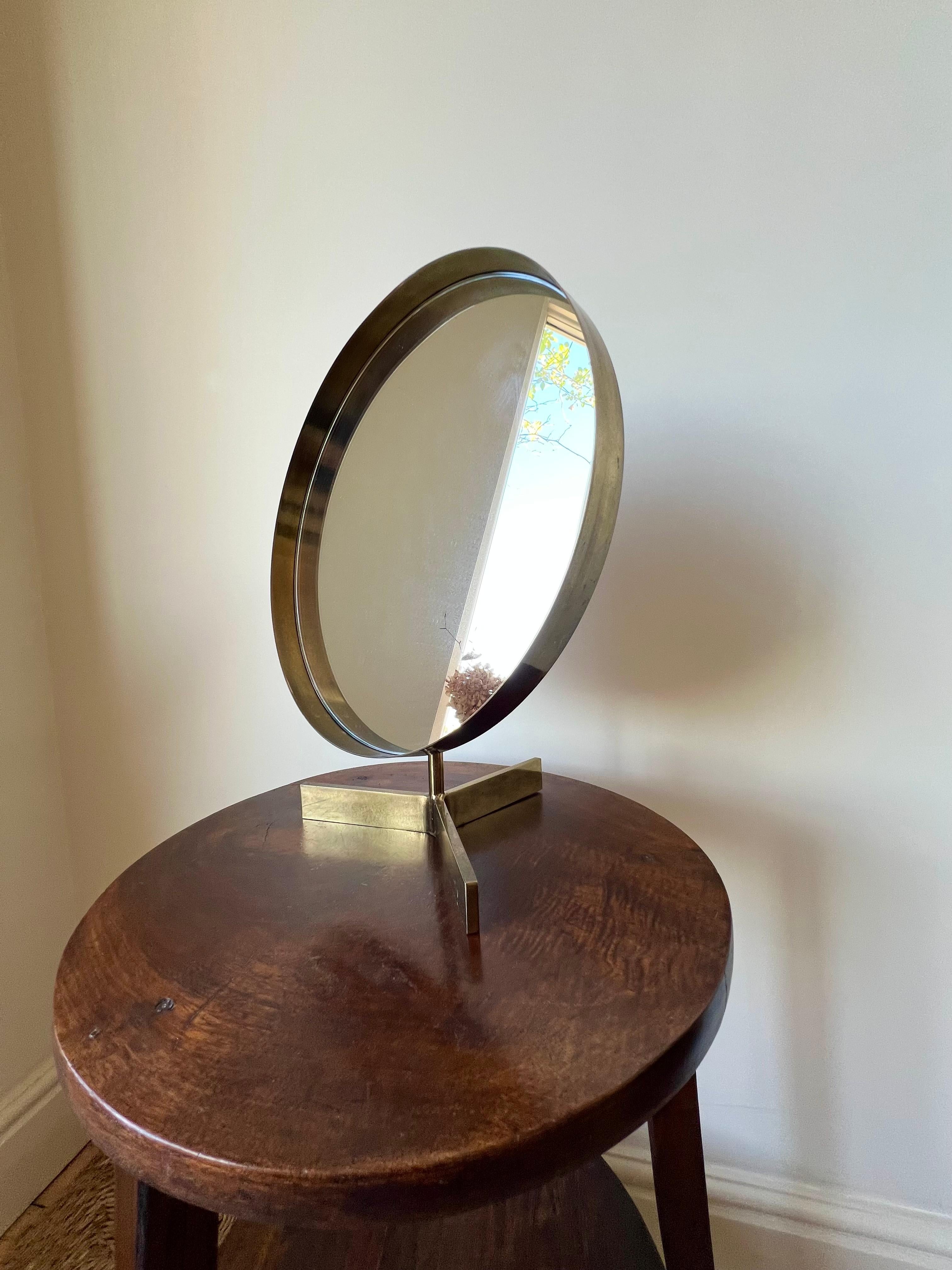 Miroir de table / de toilette rond de bonne taille datant du milieu du siècle dernier, conçu par Owen F Thomas pour Durlston Designs, Angleterre, années 1960. 

Cadre en laiton sur une base à trois branches en laiton. Le miroir se règle en