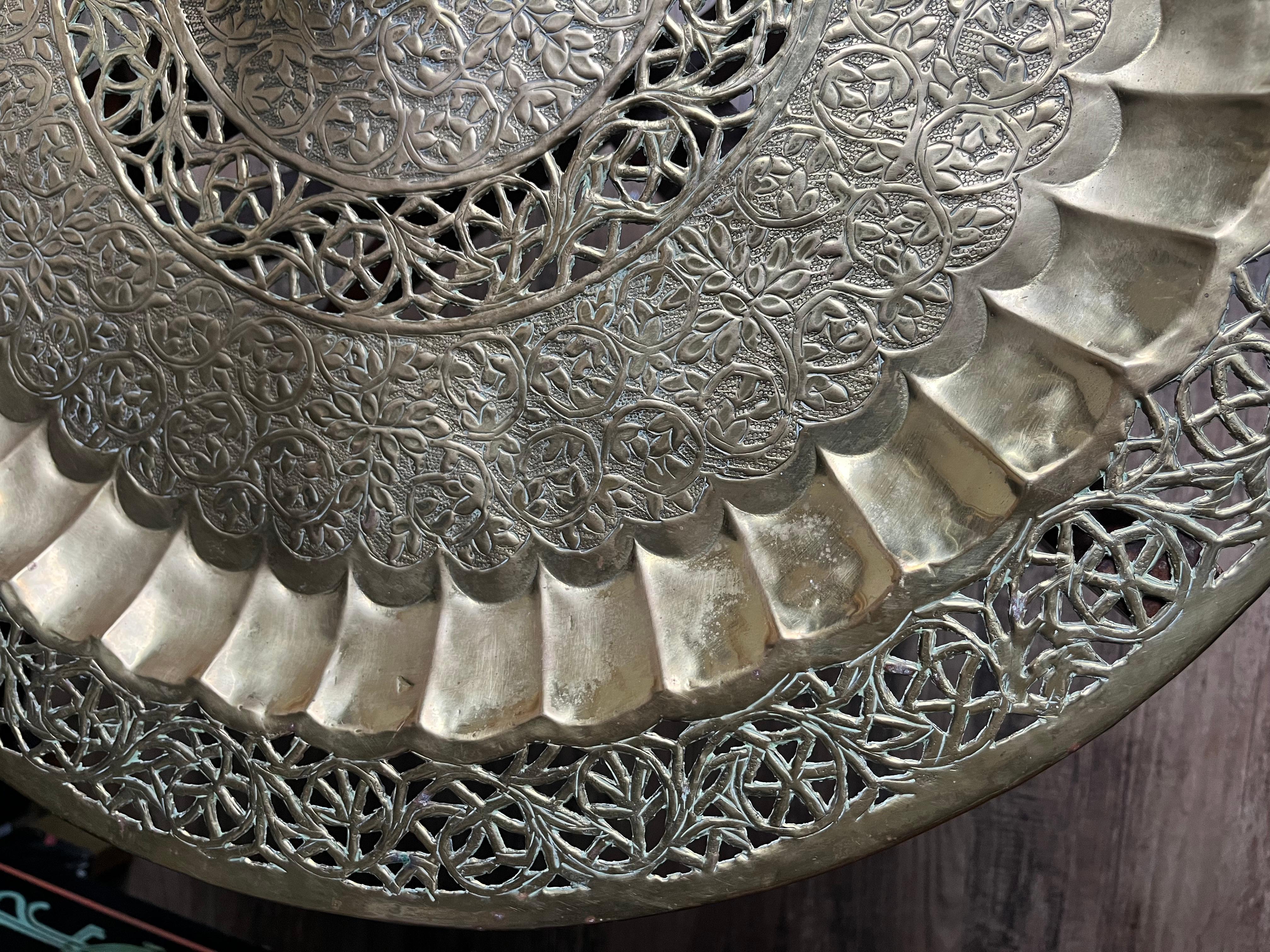 This stunning mid-century Moroccan brass table features an intricately designed brass tray top, showcasing beautiful floral and geometric patterns that exude elegance and craftsmanship. The tray is removable, making it both a functional and