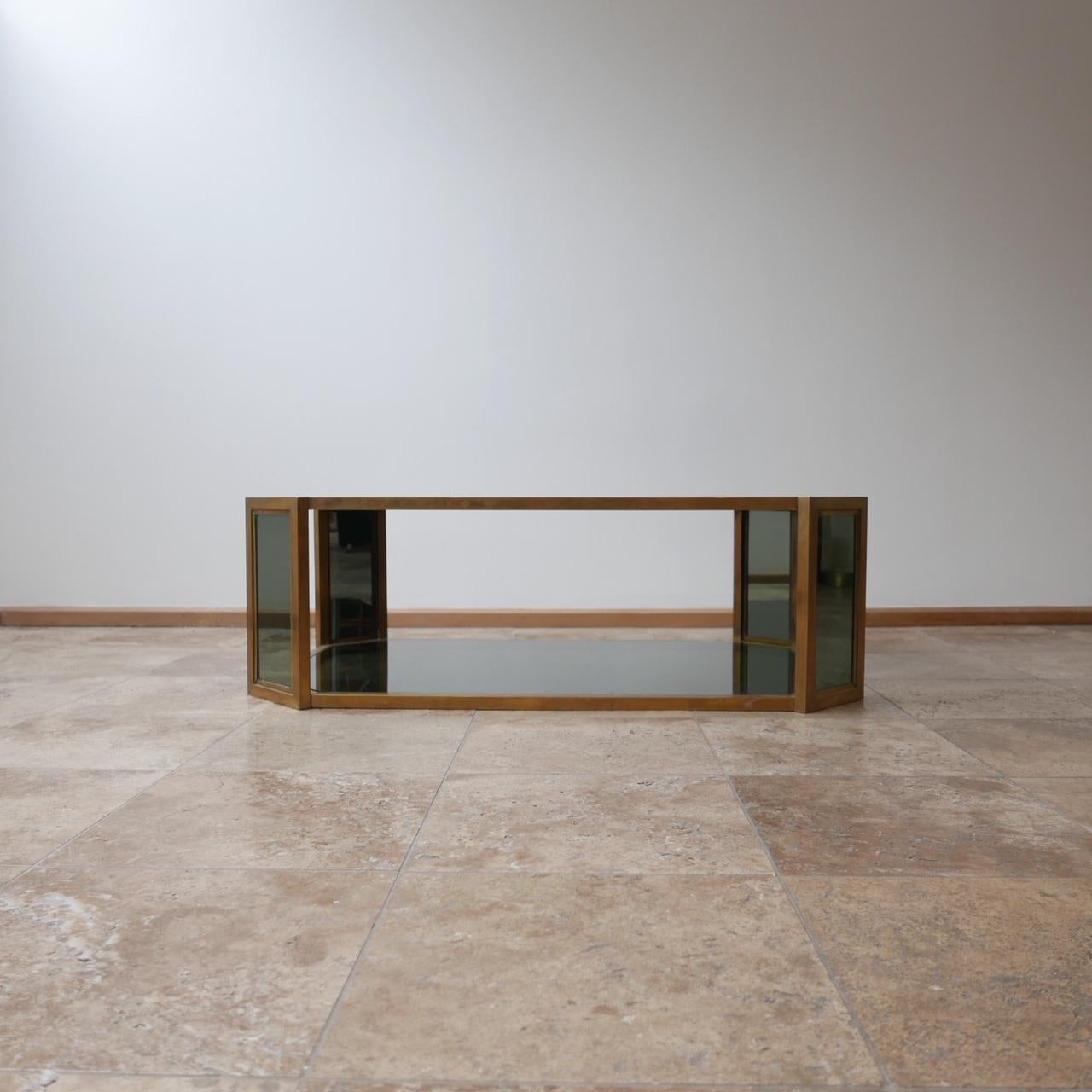 A brass octagonal coffee table.

Midcentury, French.

Two-tier smoked glass.

The four smaller angular sides also have glass.

 