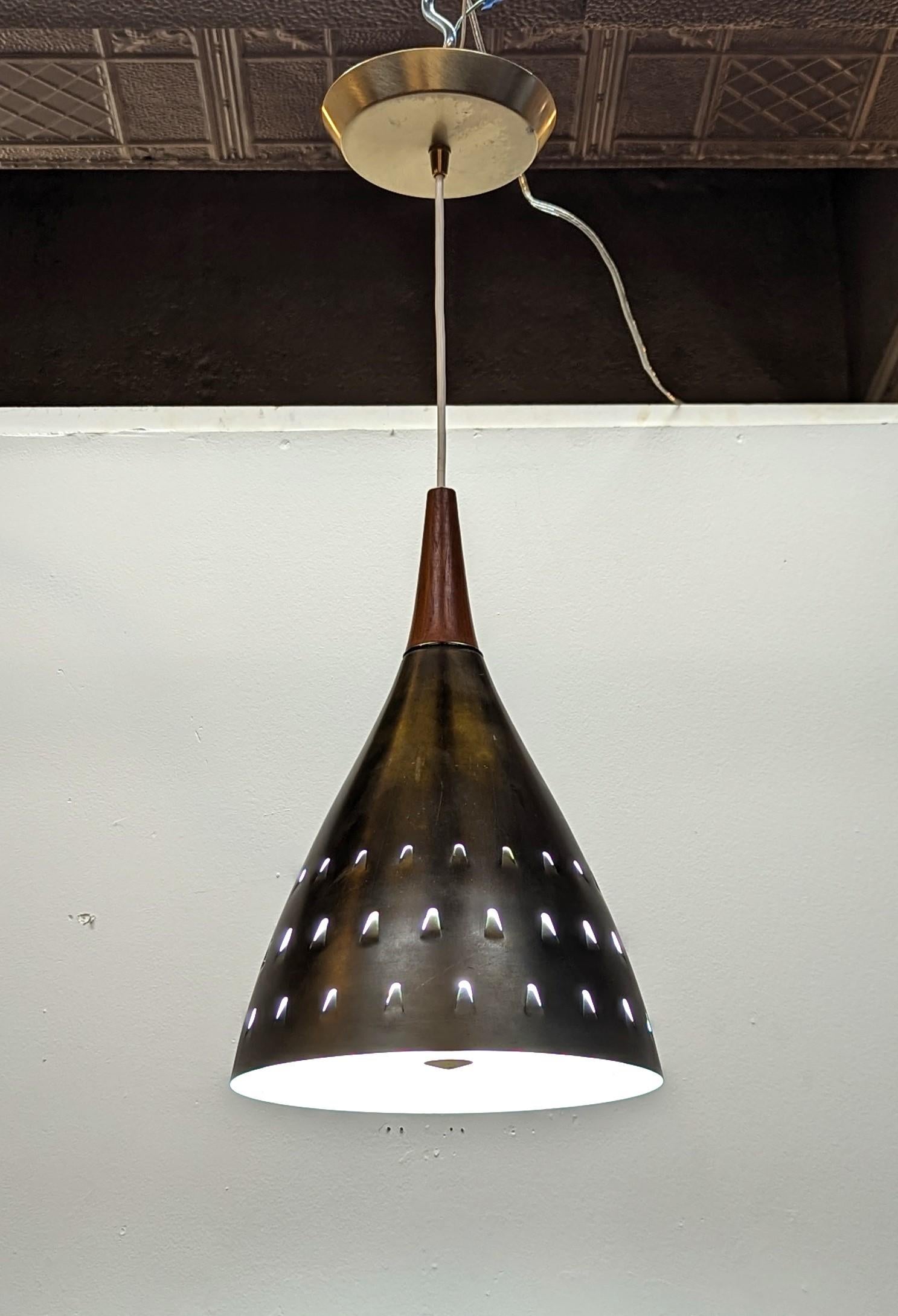 Mid Century Modern Brass & Teak Pendant Light in the style of Hans-Agne Jakobsson.  Solid brass perforated cone and brass canopy with teak finial.  Wonderful pendant light glows nicely through the U shaped perforations.  White glass diffuser allows