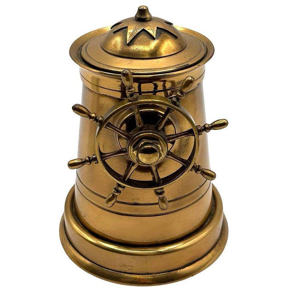 Questo portasigarette meccanico a scomparsa in ottone antico è un oggetto da collezione affascinante e funzionale, progettato come un faro. Presenta un delizioso timone di nave che aggiunge un tocco nautico al suo design. Quando la ruota viene