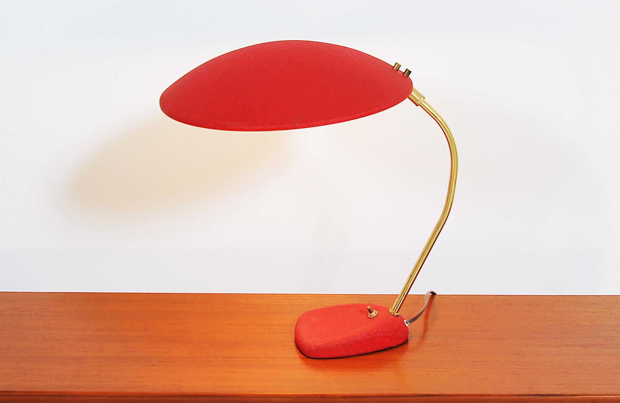 Beautiful enameled desk lamp designed and manufactured in the United States, circa 1960s. This practical desk lamp features a red enamel base and hooded shade that is sturdily supported by a polished brass neck. The shade can be rotated 360 degrees