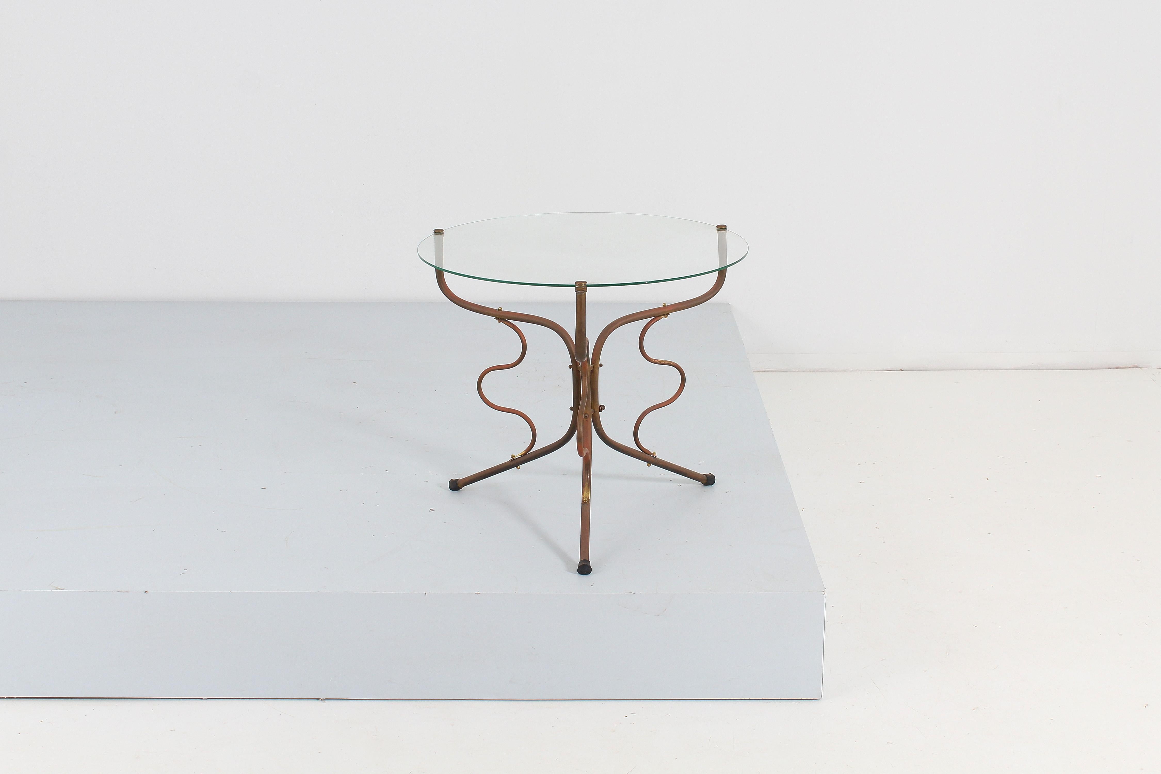 Table basse élégante avec plateau circulaire en verre et structure artistique à trois pieds en tige de cuivre incurvée et ondulée. Production italienne des années 50