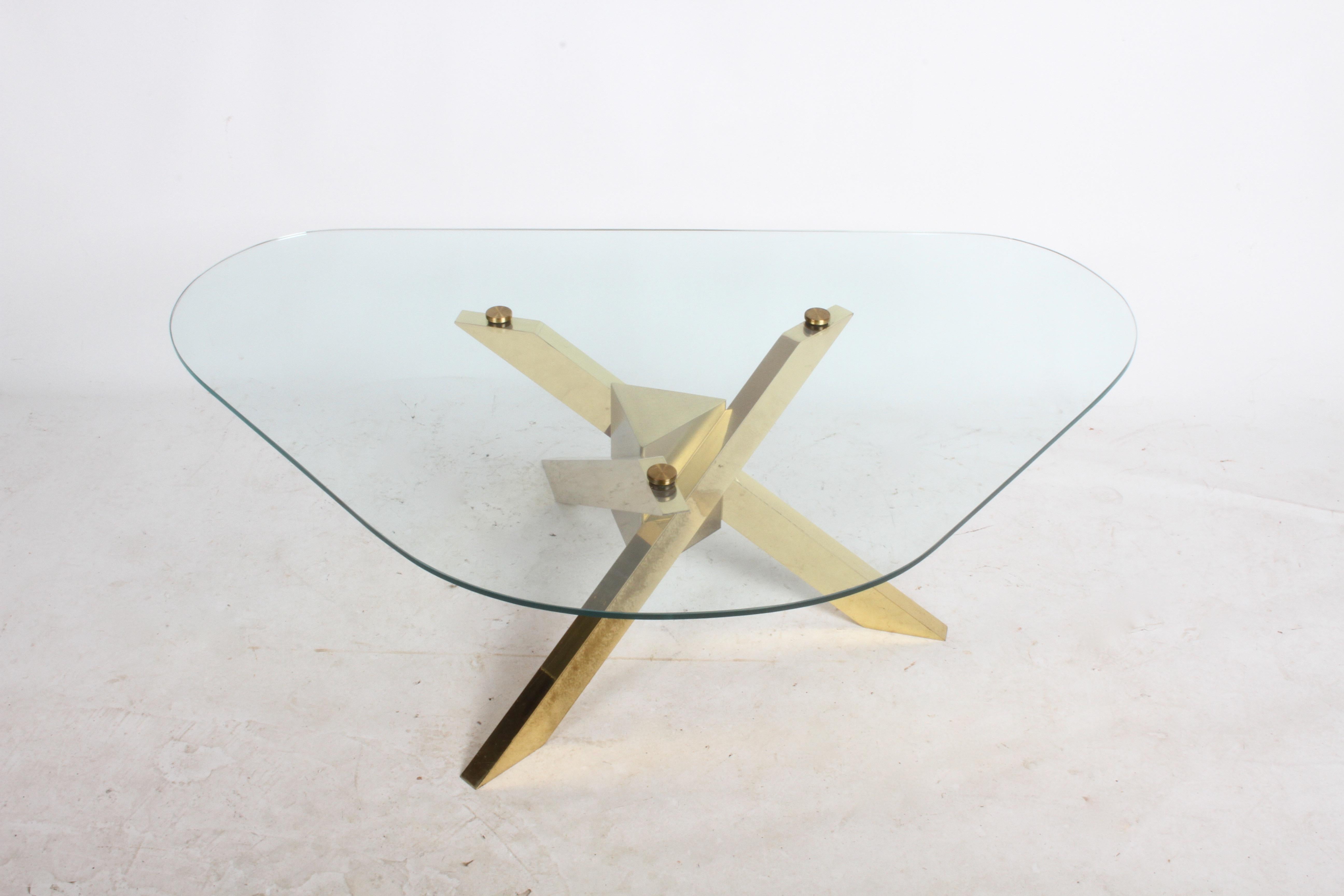 Brass tripod architectural base with rounded edge triangular form glass top. Brass base shows light patina, (can be professionally polished for additional cost, inquire on price) no chips to glass only light scratches. Top attached to base with