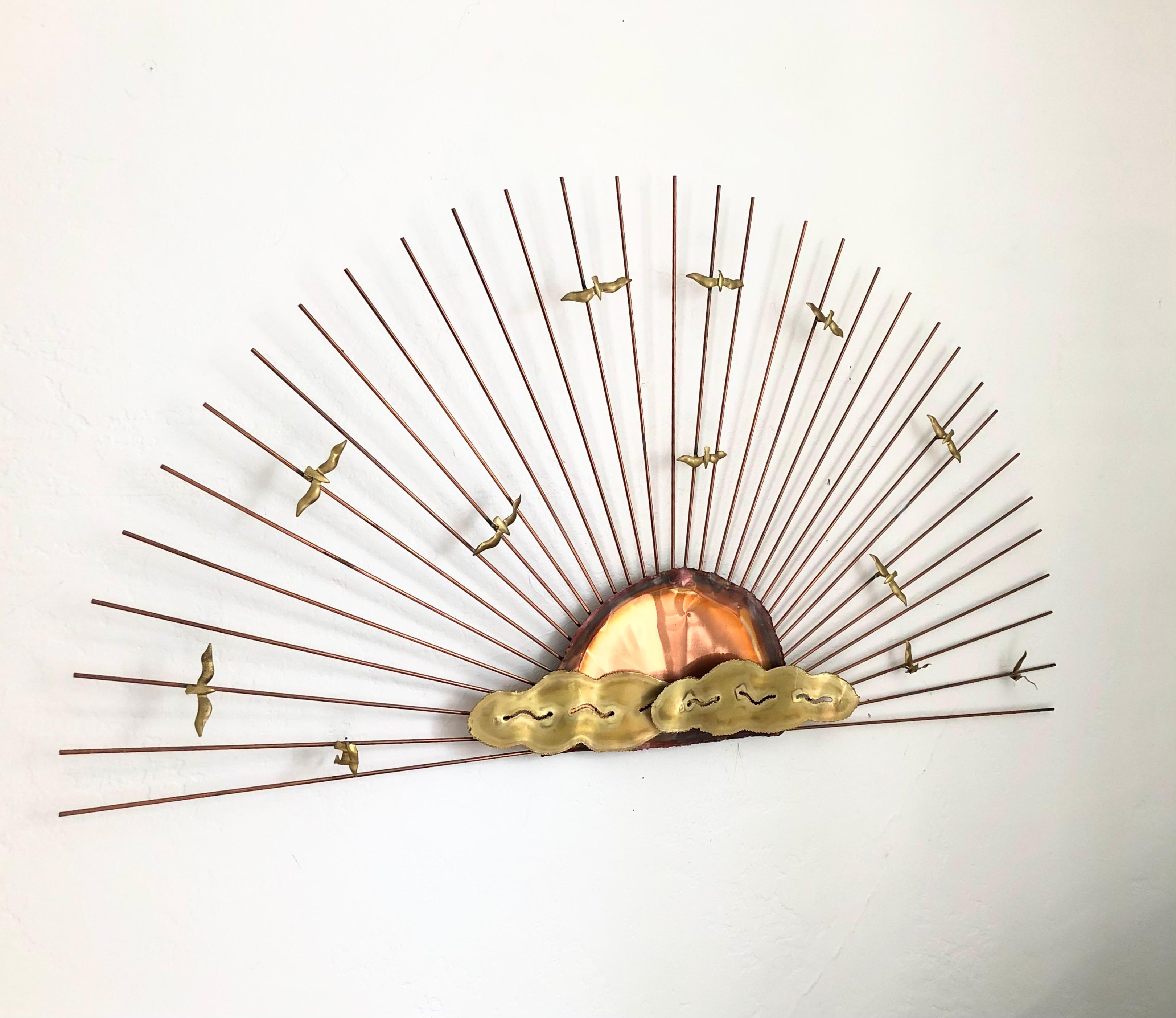 A mid century brass seagull sunburst wall hanging in the style of Curtis Jere. Thin brass rods have been arranged in a semi circular shape around a copper and brass sun in the center to create a sunburst effect. And organic arrangement of small
