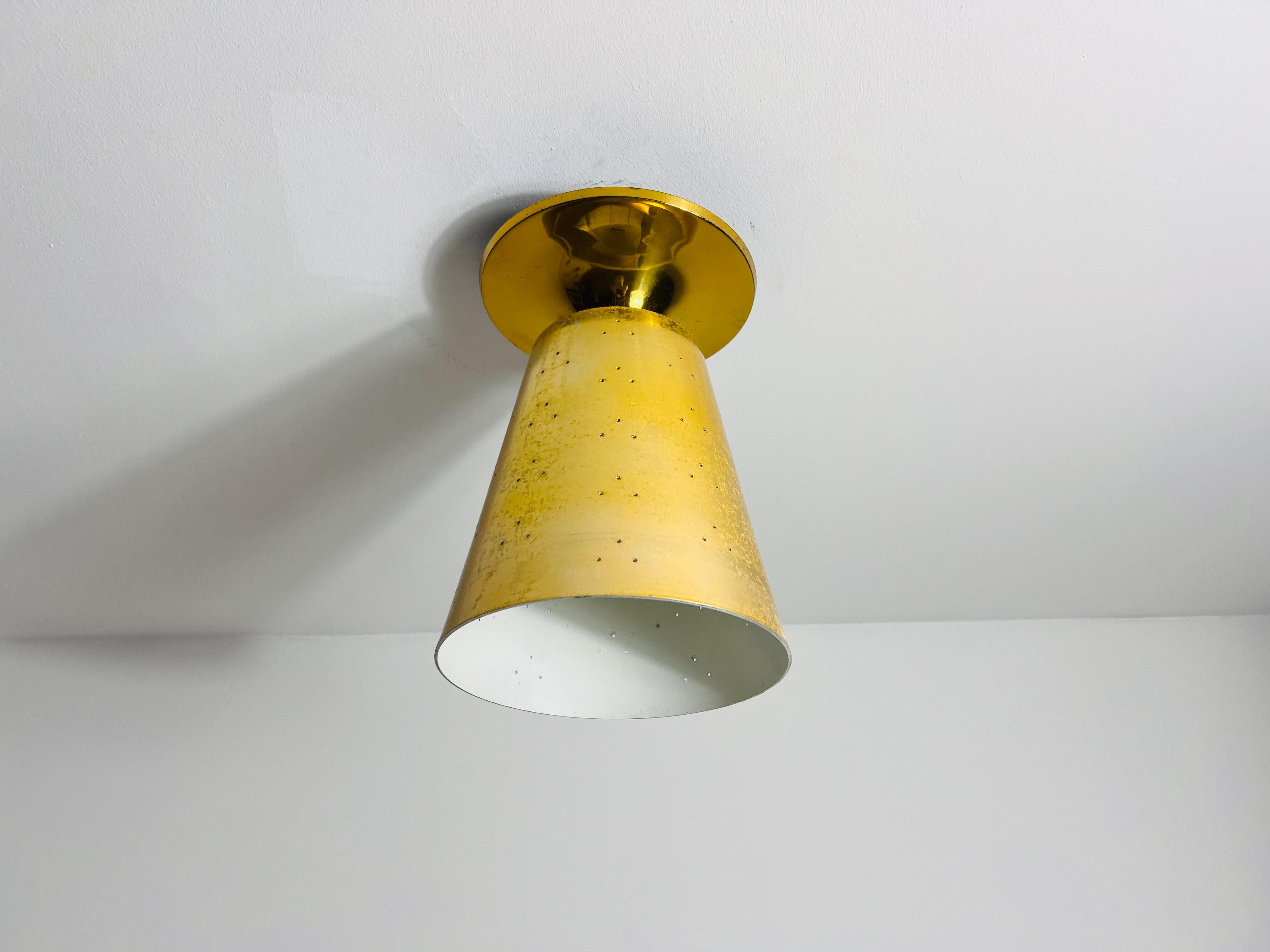 This vintage ceiling lamp from the 1960s showcases the refined elegance of Italian mid-century design. Crafted from solid brass, the lamp features a tapered conical shade with a beautifully aged patina, adding a touch of character and authenticity