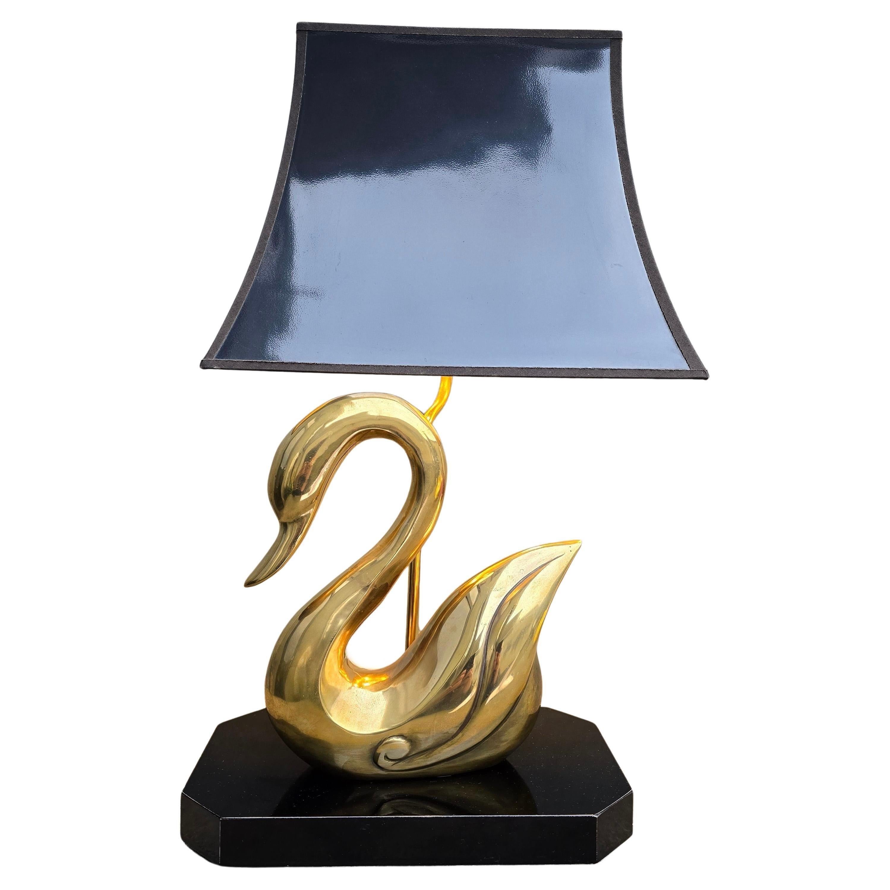 Lampe de table Swan en laiton du milieu du siècle avec abat-jour noir et intérieur doré

Conçue en forme de cygne gracieux, cette lampe est dotée d'un corps en laiton massif aux courbes élégantes et sculpturales qui reflètent une chaude lueur dorée.