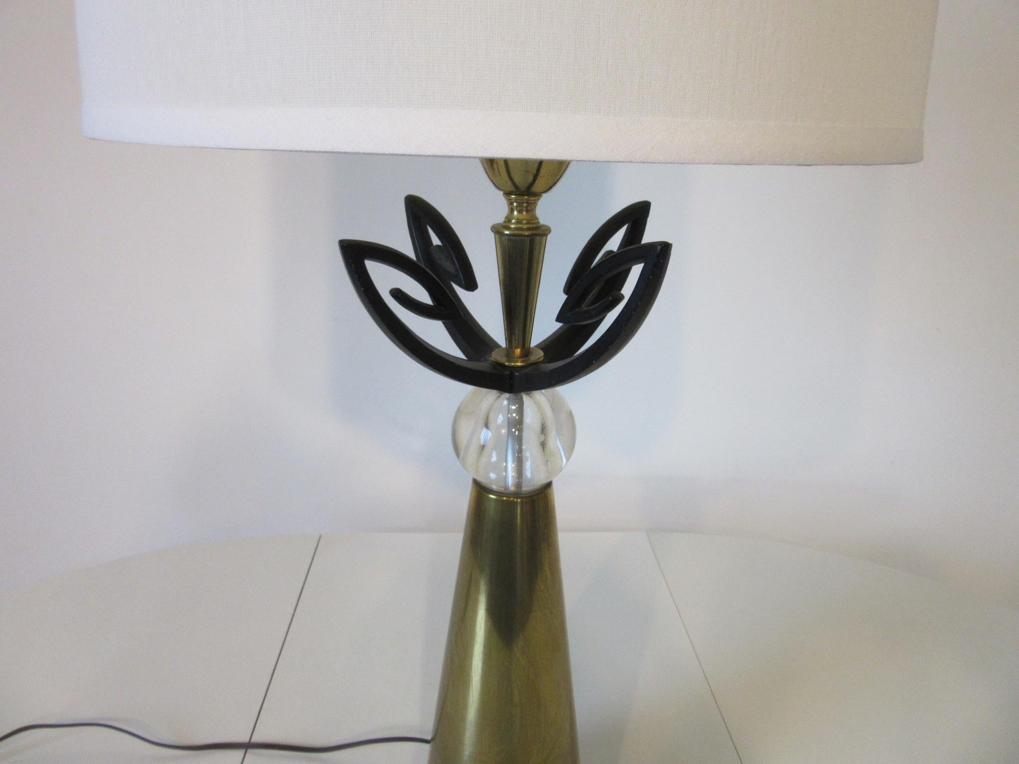 A decorative 1950's table lamp with brass base , sculptural metal work in stain black and a handblown glass ball to the shaft . Topped with a linen shade manufactured in the quality and style of the Rembrandt Lighting company made by Aurora .      