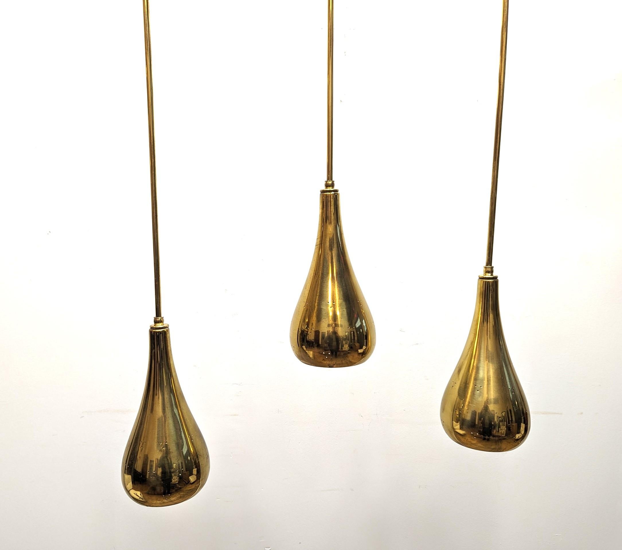 Sensational Brass Tear Drop Pendants attributed Paavo Tynell for Lightolier.  The Pendants are solid brass with a three hole triangular perforated pattern design detail.  The rounded shapes slightly turned in on the openings are finely sculpted.  
