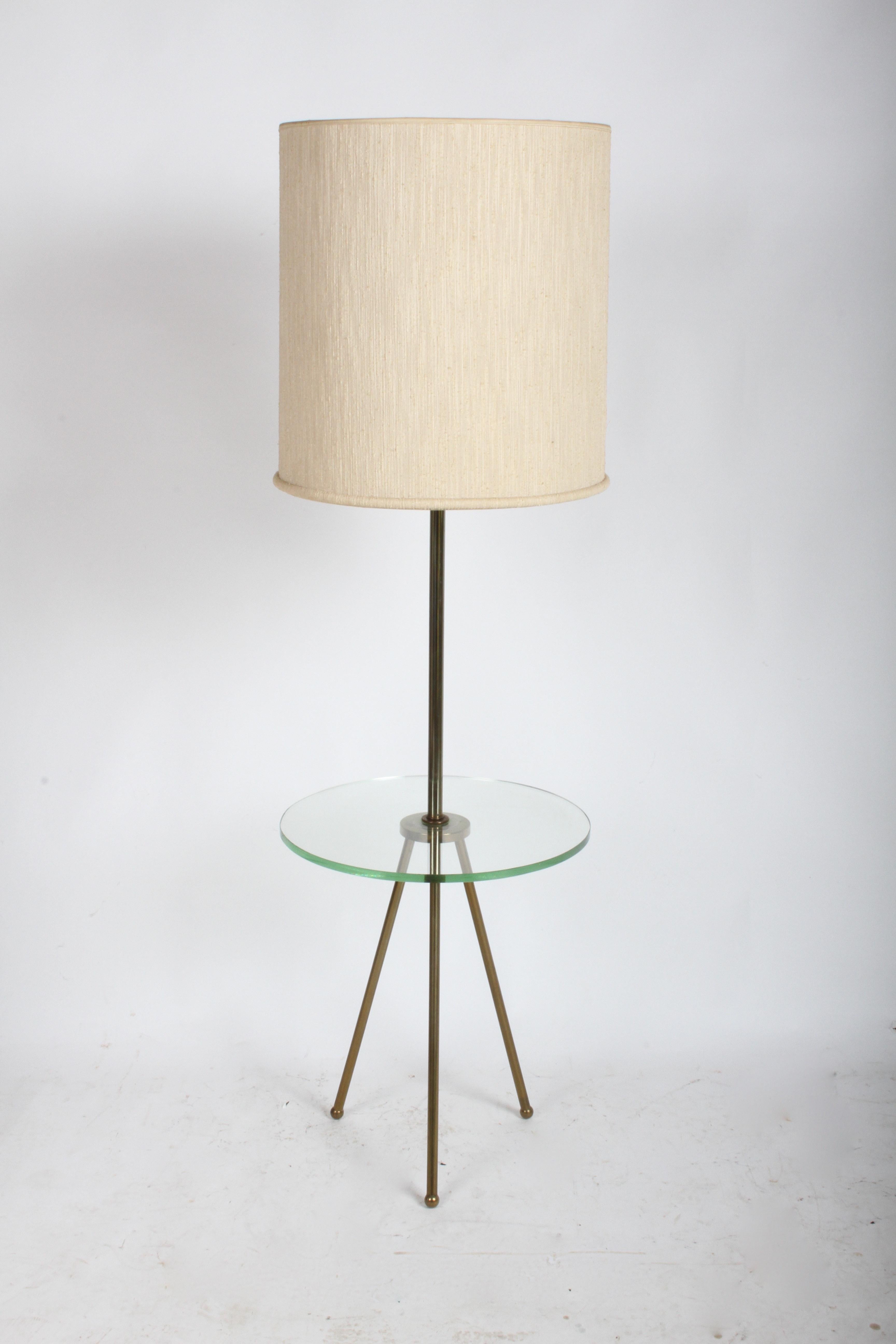 Mid-Century Modern floor lamp having brass tripod legs with round glass shelf, in the style of Fontana Arte. Unknown designer, but also has the look of Italian modern designers. Shade not included, shade specs shown are 19