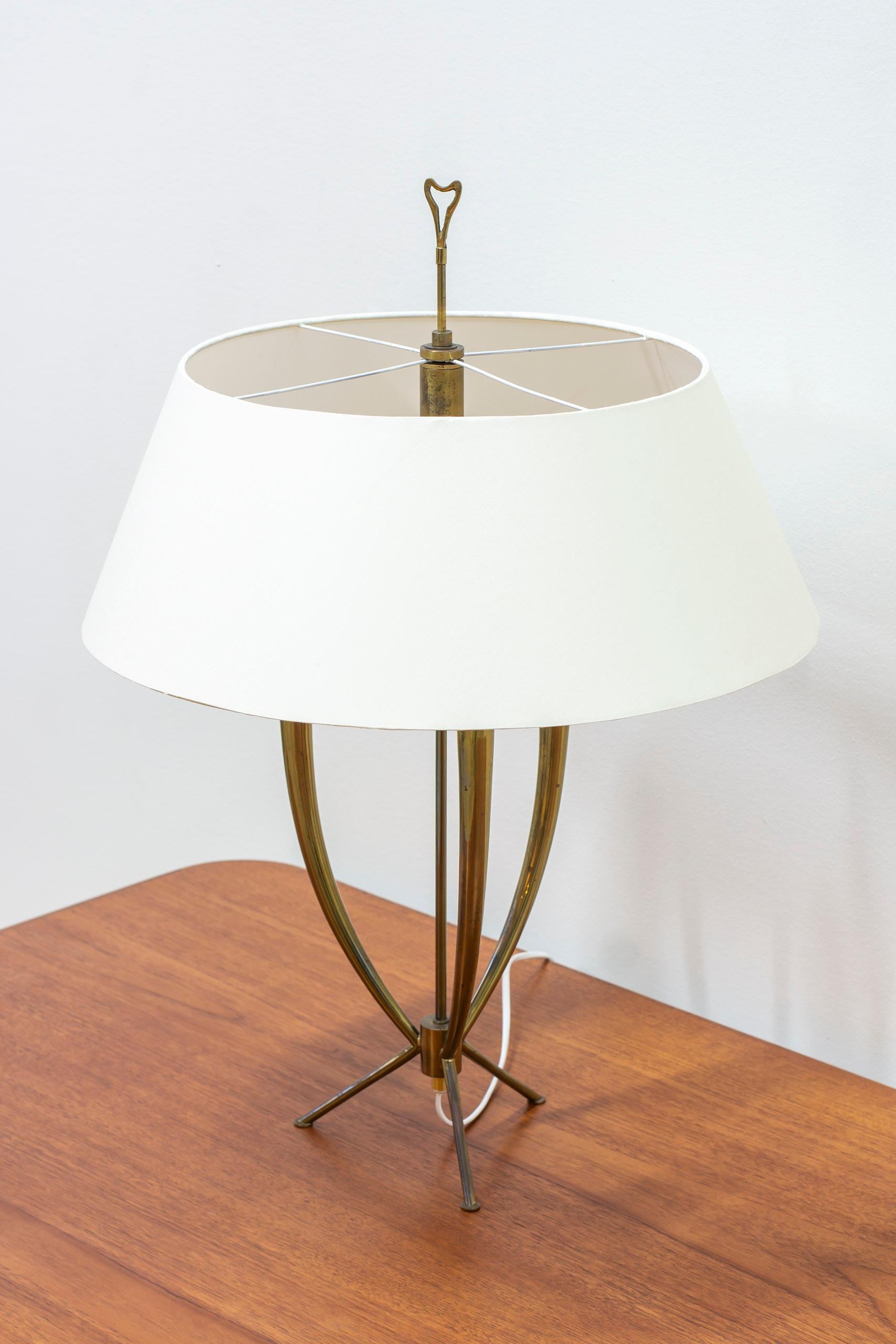 Grande et inhabituelle lampe de table à trépied. Fabriqué dans les années 1950 en laiton massif poli avec un très haut niveau d'exécution et de finition. L'abat-jour d'origine a été recouvert d'un tissu en coton chintz de couleur crème. La partie