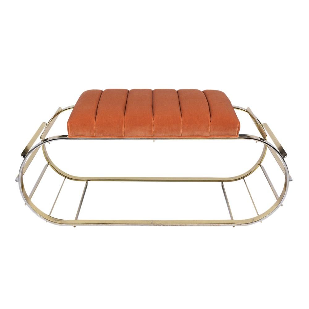 This unique Mid-Century Modern brass bench is in good condition, features a unique oval base design, and has been newly polished. The seat cushion has been upholstered in a new orange color mohair fabric and given a tufted channel design with single