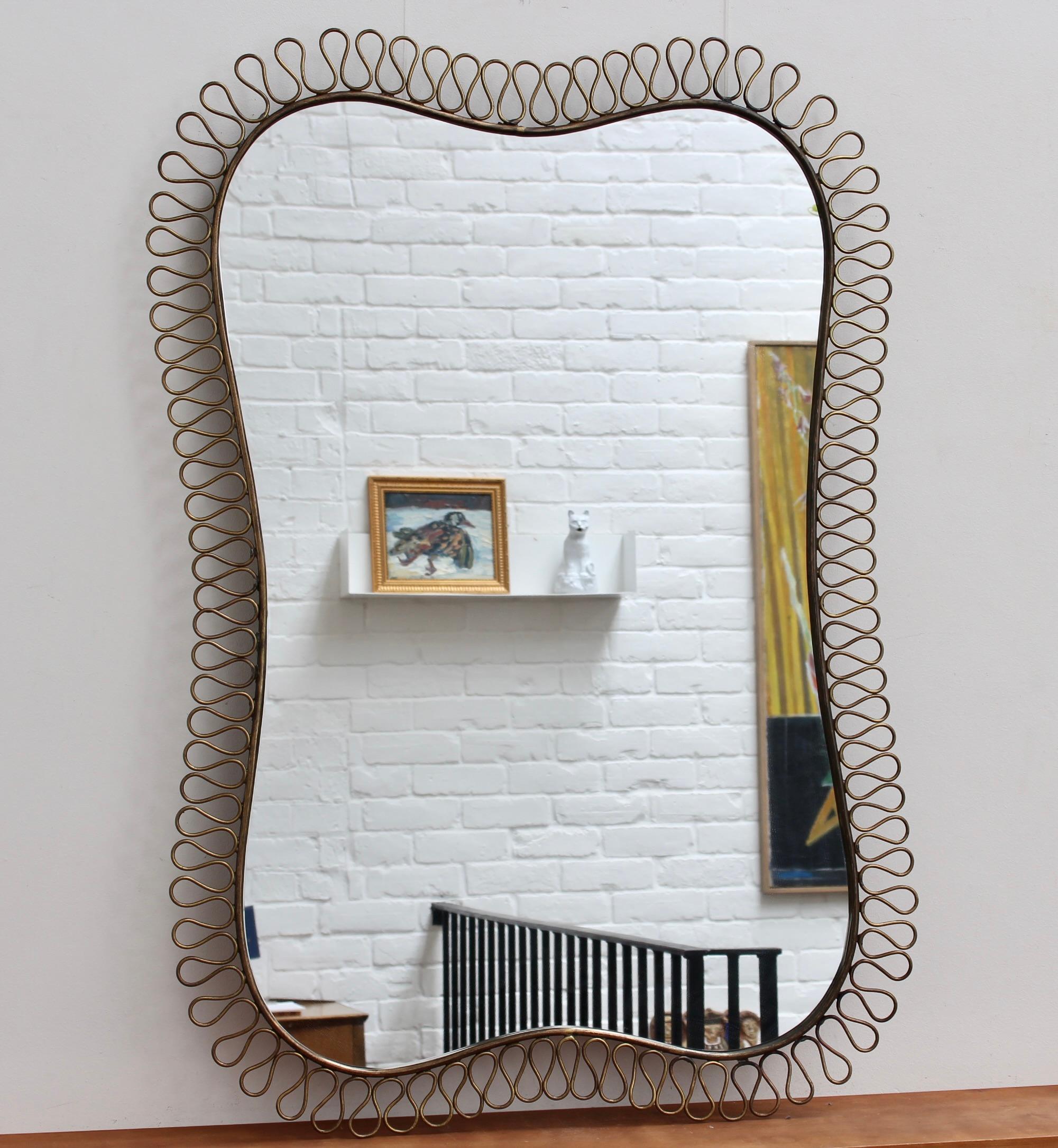 Vintage brass wall mirror with decorative corona-effect surround in the style of Josef Frank (circa 1960s). Original design, elegant presence and confident, quirky shape, this mirror is the centre of attention in any room and is a rare find indeed.