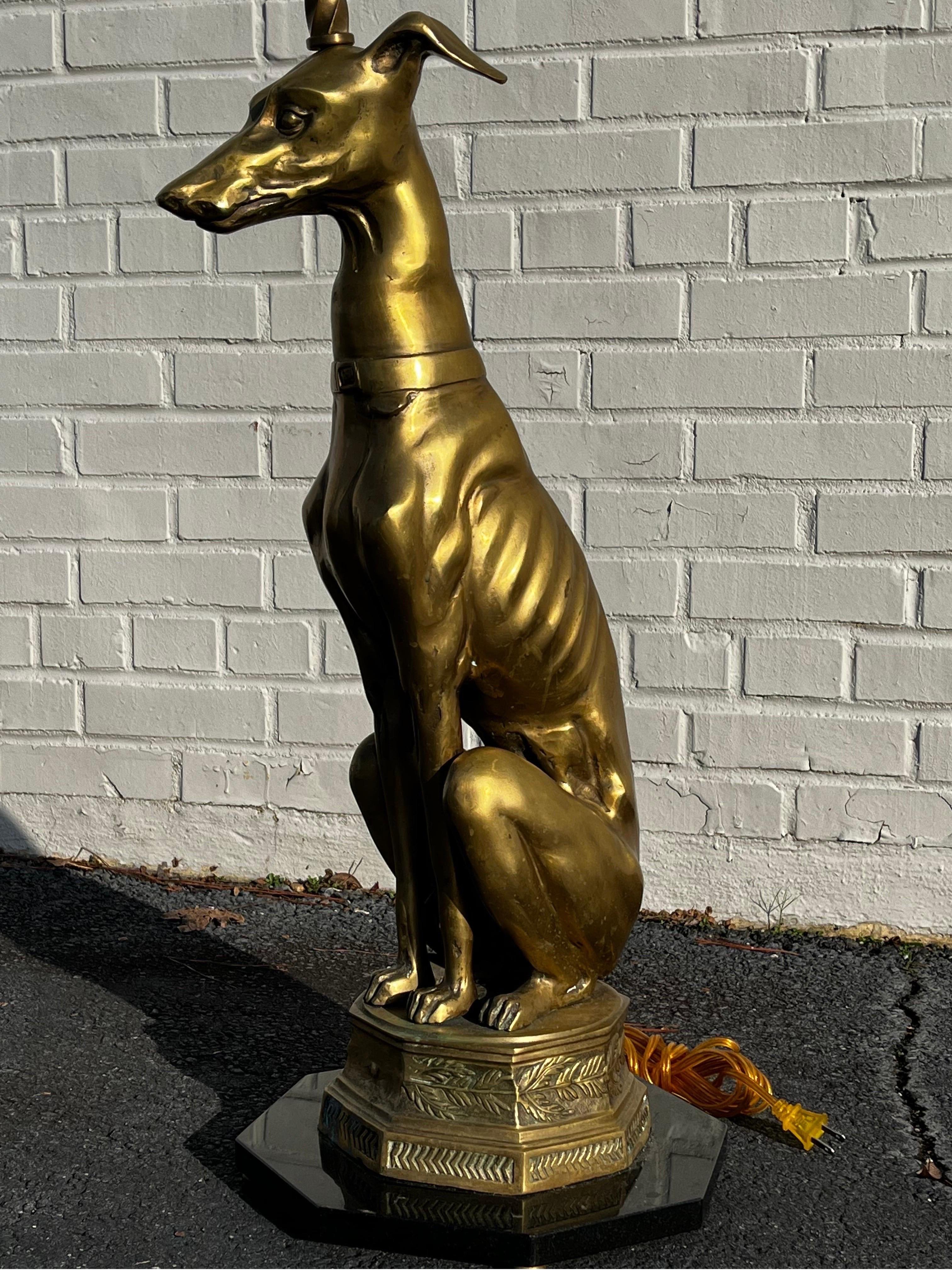 A mid 20th century cast brass sculpture of a seated Greyhound / Whippet dog presented on an integral brass octagon shaped plinth style base with running leaf and geometric ornament. The sculpture is secured to an octagon shaped piece of polished