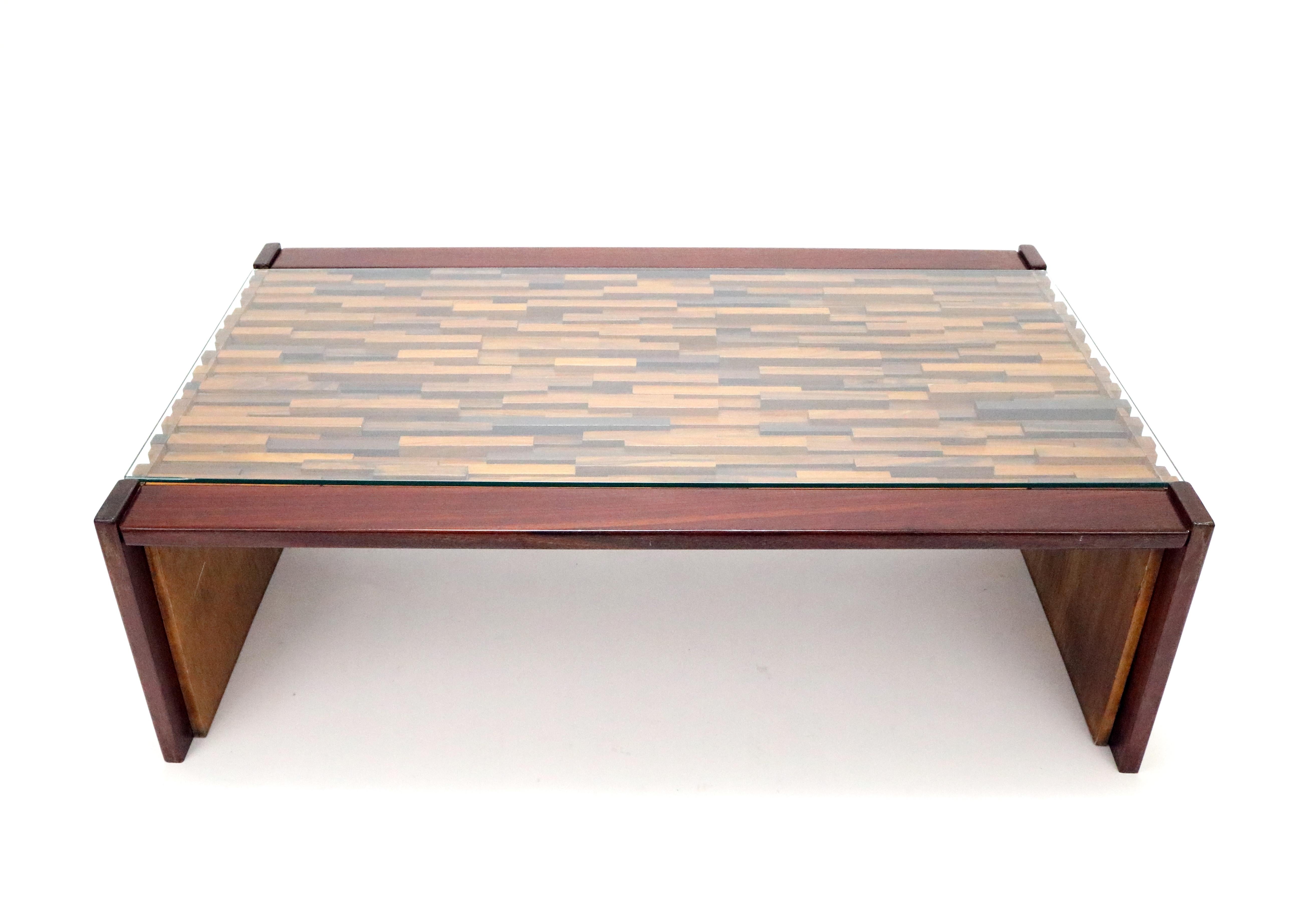 A midcentury Brutalist coffee table by Percival Lafer, Brazil, 1970s. A beautiful mosaic of rosewood, teak and jacaranda woods extend under the glass top and down two sides.