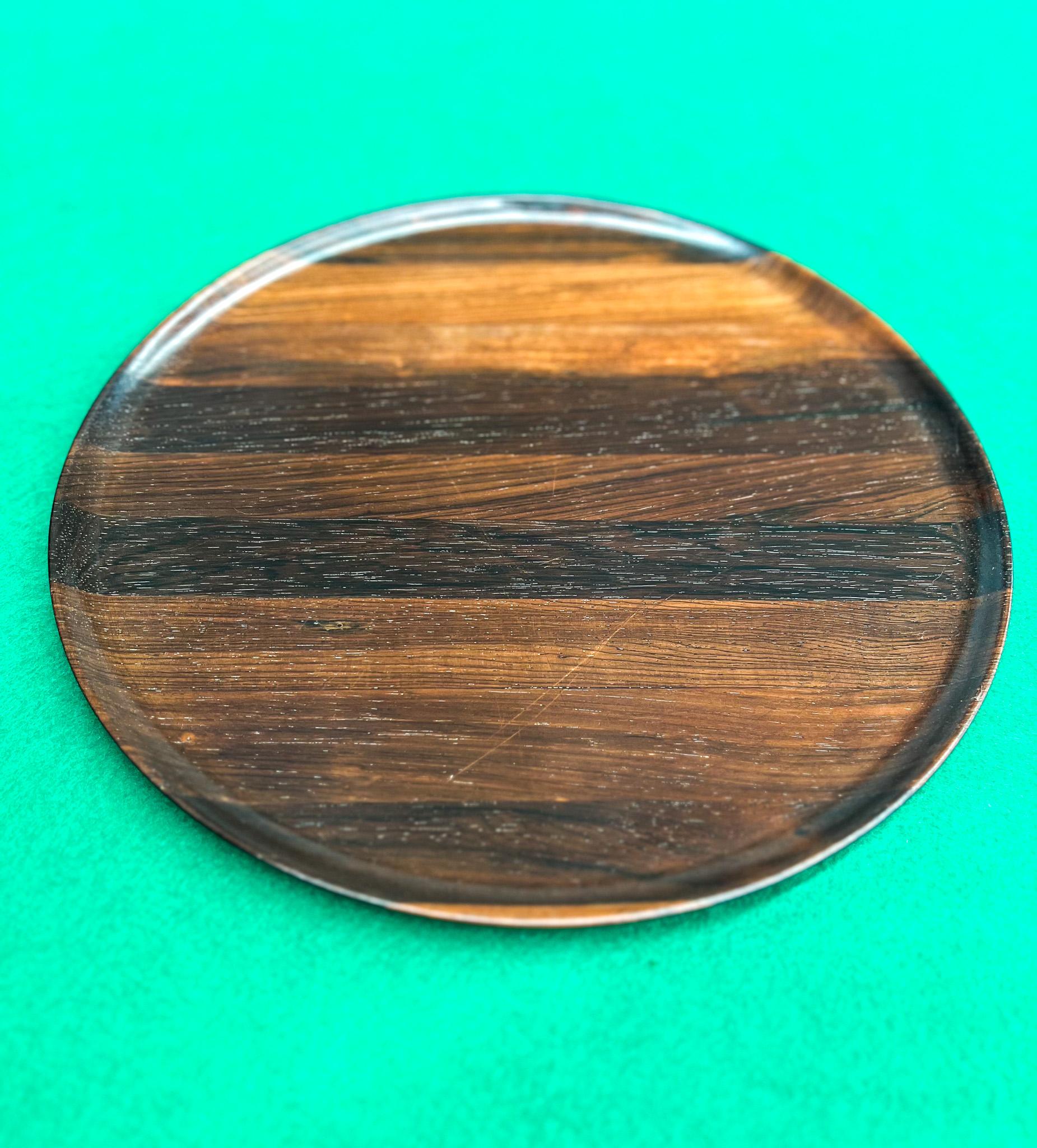 Available today, this midcentury Brazilian Modern Rosewood decorative plate was designed by Tropic Art and made in Brazil circa 1960. Handcrafted from hard Rosewood (known as Jacaranda), the plate features a circular shapes with round edges. The