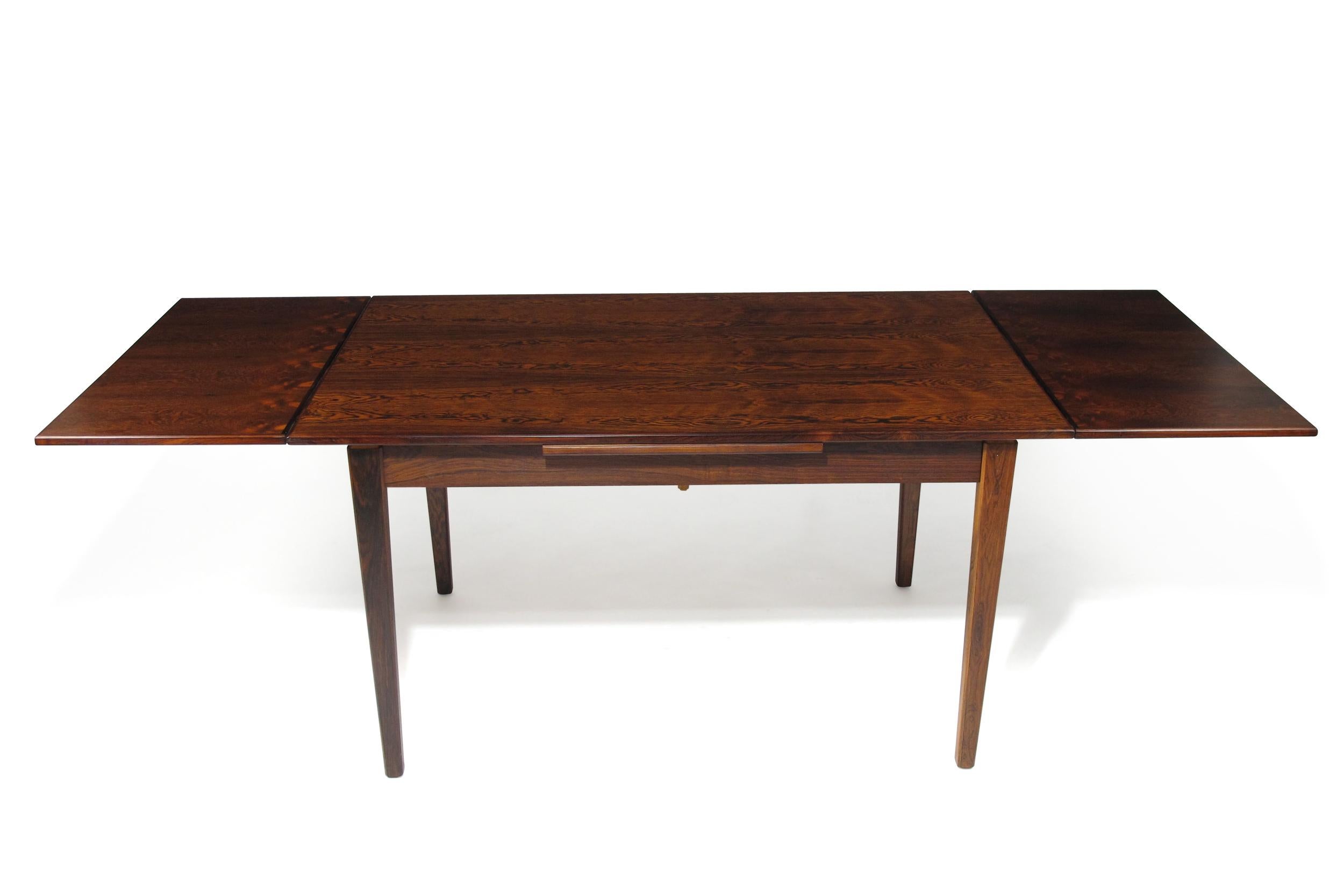 Midcentury Brazilian Rosewood dining table with draw-leaves manufactured in Denmark circa 1955. Dining table crafted of dark rosewood dramatic grain.Seats six closed, up to ten guests with pull-out leaves extended. Finely restored in a natural oil