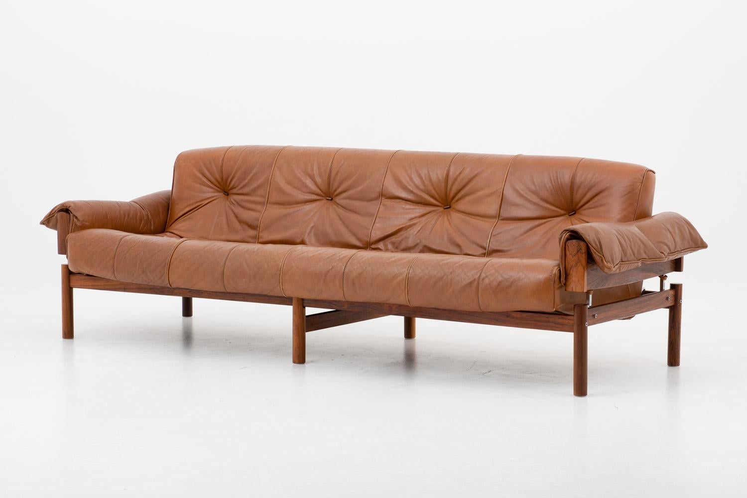 Four-seat sofa by Percival Lafer, Brazil, 1960s. 
This sofa consists of a rosewood frame upon which the cushions rest. The cushions are upholstered in brown leather with buttons of rosewood on the seating and backrest. The armrests are held in