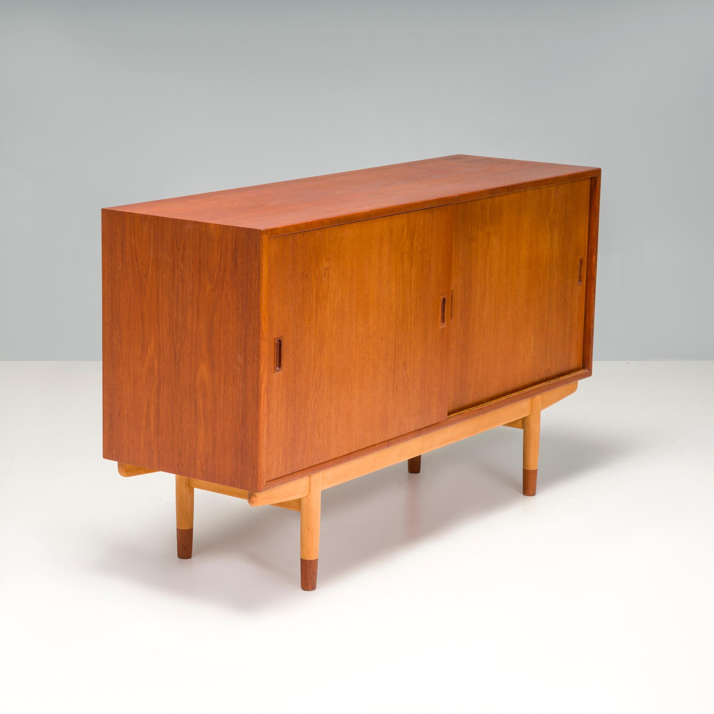 Produced in Denmark during the 1950s by Søborg Møbelfabrik, it features two sliding doors which open to reveal a beech-lined interior with two adjustable shelves and four dovetail-jointed drawers. The teak carcass is mounted on a beech frame and the