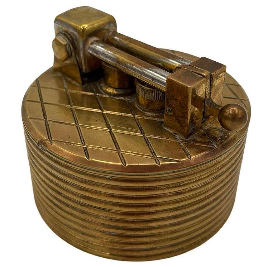 This 1950s Brilux for Dunhill Swiss brass lift-arm table lighter combines timeless elegance with exceptional craftsmanship. Its solid brass body features a warm vintage patina, and the smooth lift-arm mechanism highlights Swiss precision.

As a
