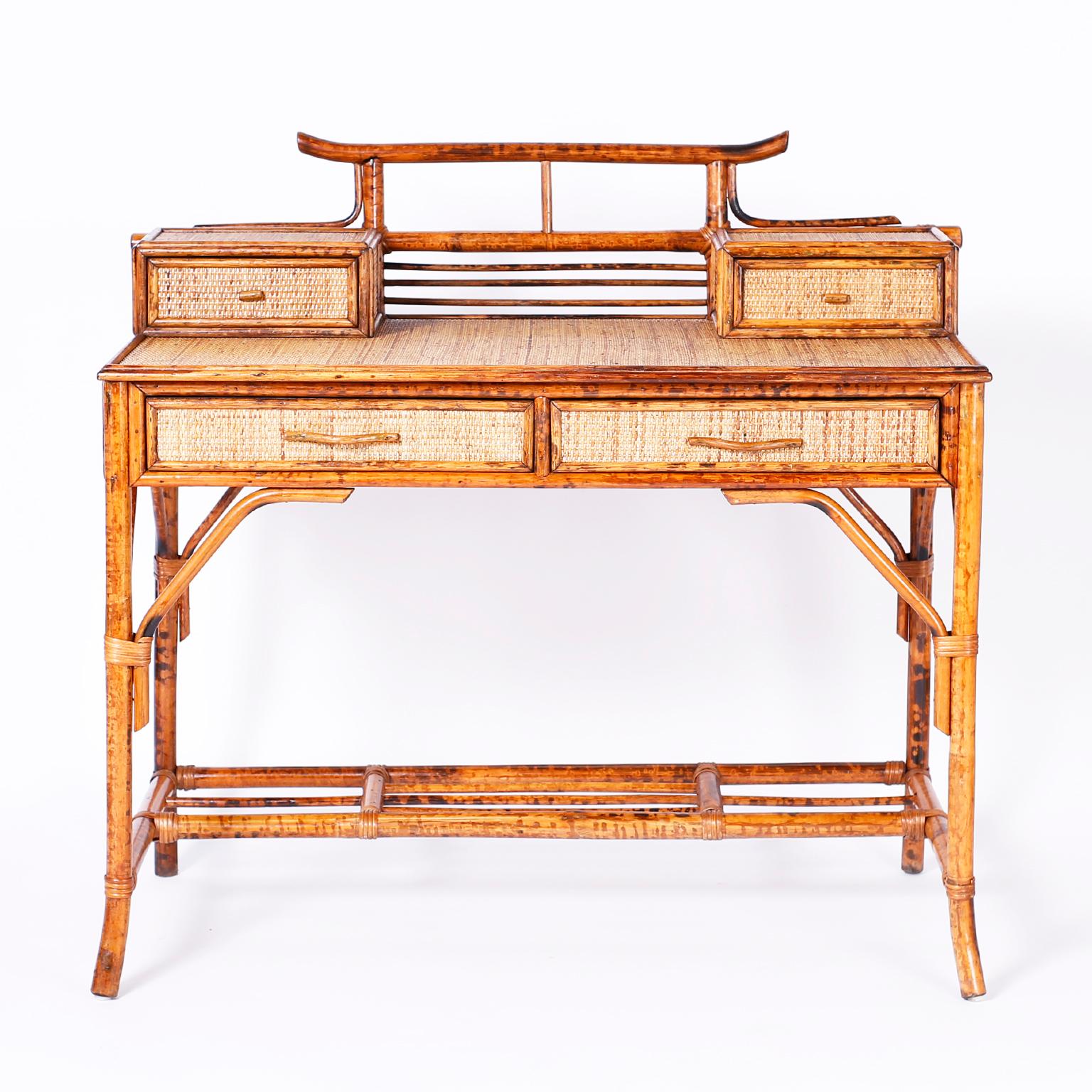 British colonial style desk with a tortoiseshell bamboo frame including a pagoda shaped gallery and grasscloth surfaces.