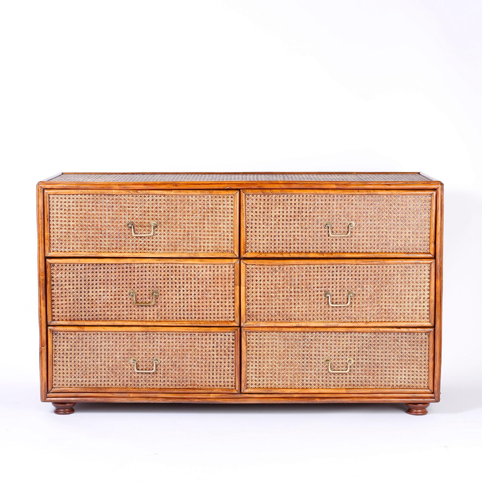 Midcentury British Colonial style six-drawer chest, dresser or credenza with a rattan frame over a caned background with brass hardware, turned feet, and a casual, elegant form.