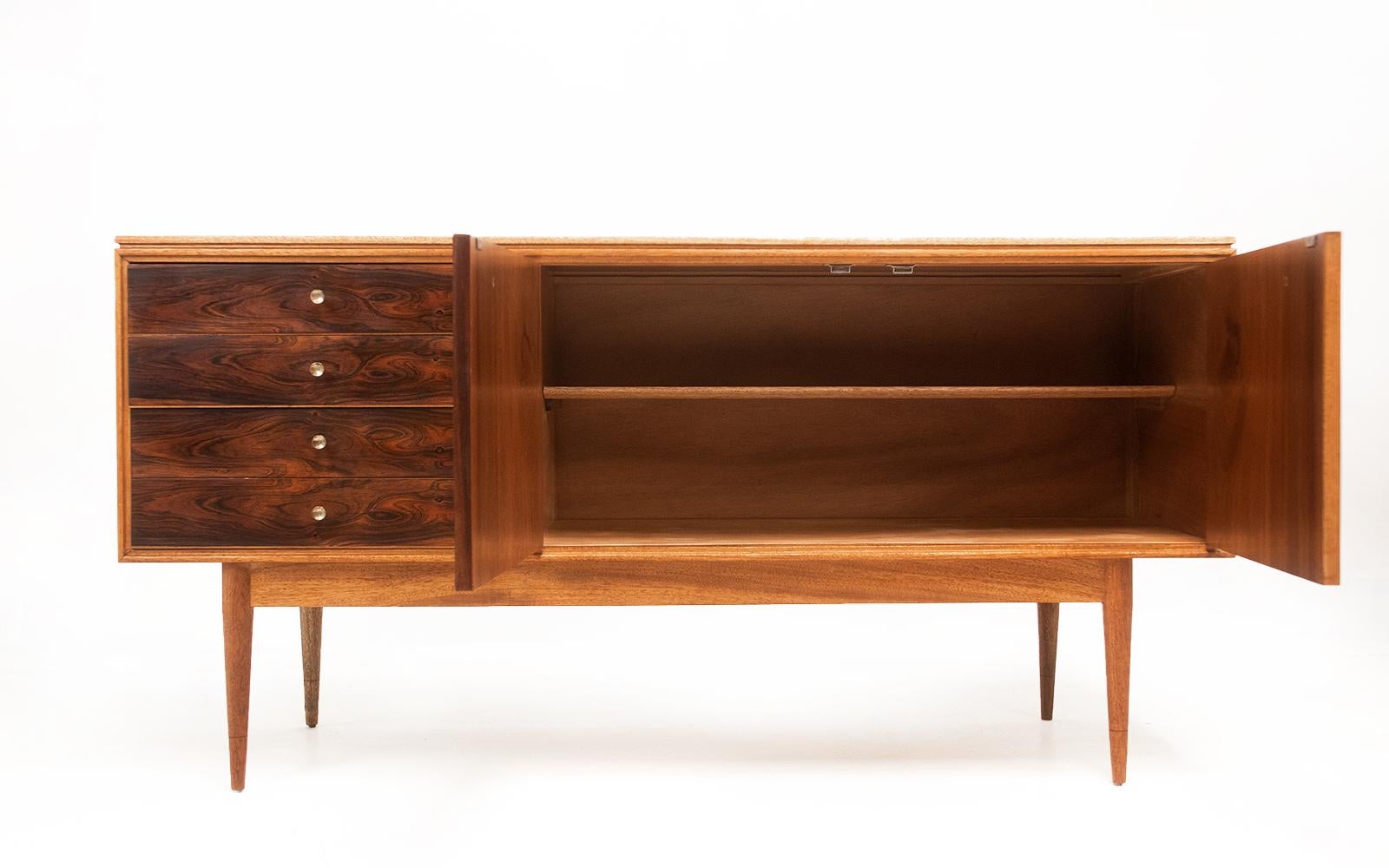 Archie Shine sideboard

Offered for sale a sort after Archie Shine ‘Hanover’ compact sideboard, this rarely available compact design with four drawers with recessed brass trumpet-shaped handles inset into the Rosewood. Two doors with matching