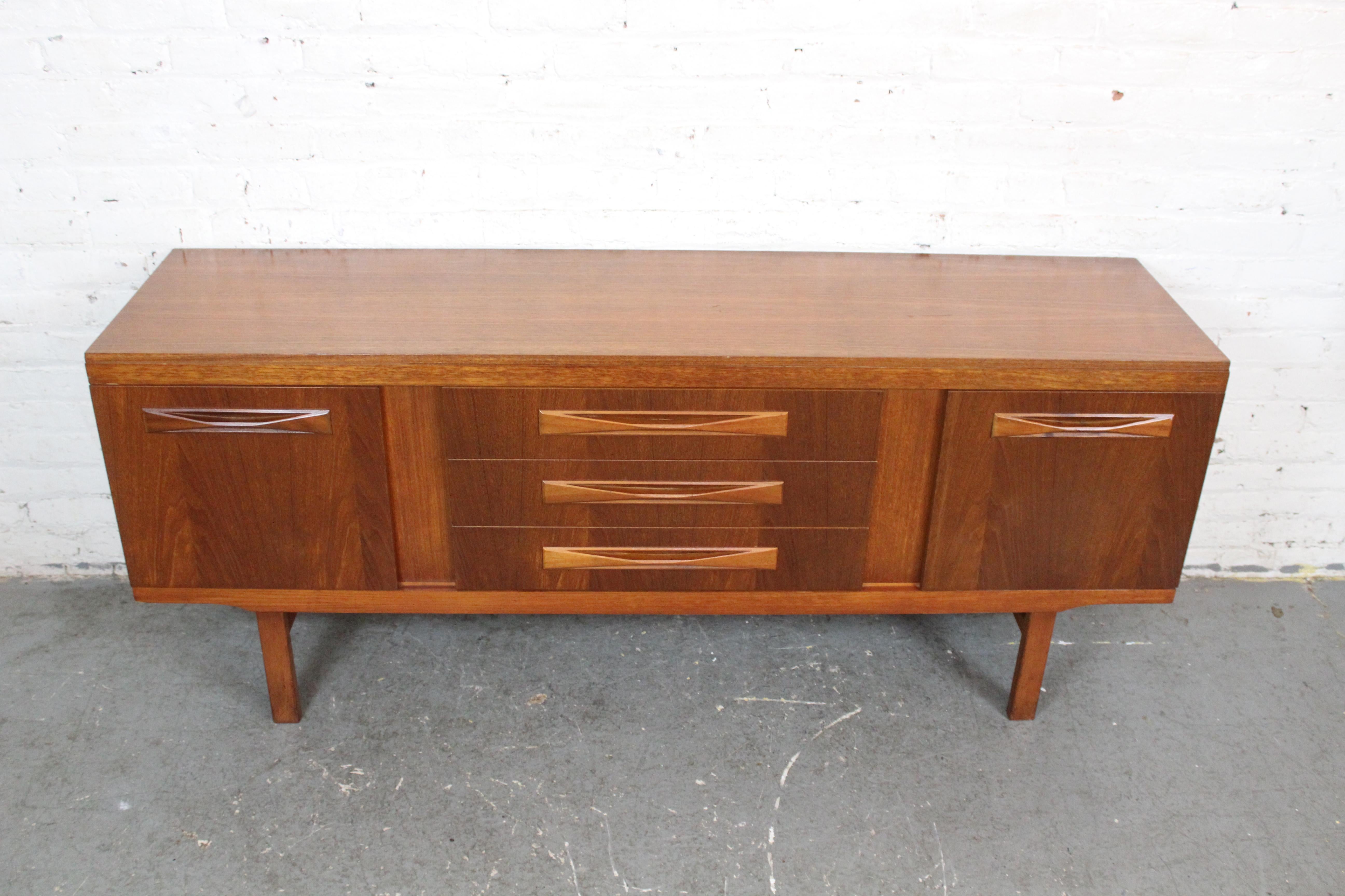 Donnez une touche internationale à votre décoration intérieure avec ce superbe buffet vintage venu d'outre-Atlantique ! Ce meuble rétro met fièrement en valeur l'approche unique de la Grande-Bretagne en matière de design moderne du milieu du siècle,