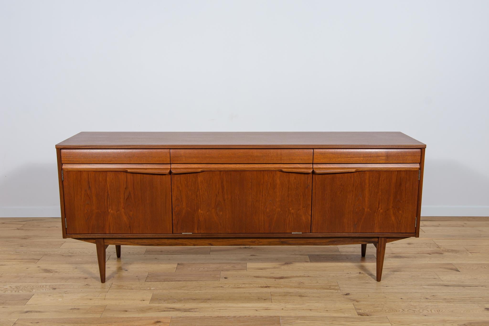 The  teak sideboard was produced in Great Britain in the 1960s.The sideboard is a flagship example of the high level of British design of the mid-20th century, as evidenced by the shape of rounded drawers and handles, perfectly integrated into the