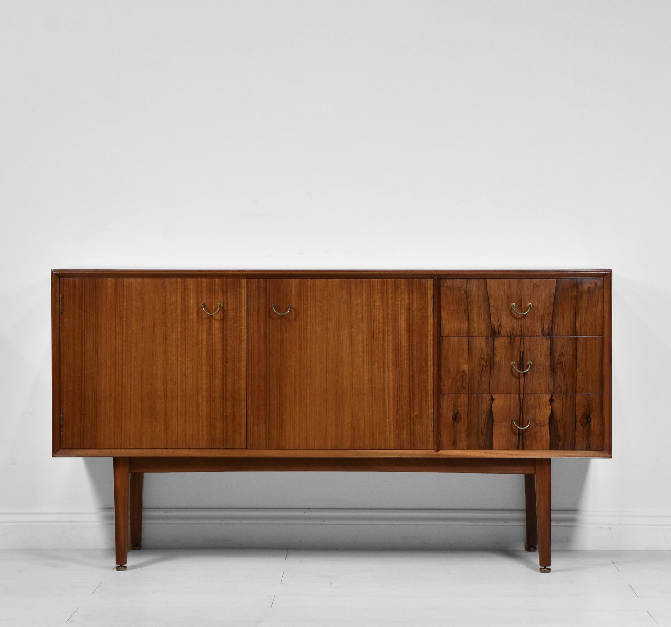 Mid-century tola sideboard with contrasting Santos rosewood drawers. British - Circa 1950.

The sideboard is in excellent condition, and has been cleaned and waxed. The drawers have solid wood sides and backs with dovetail construction. The top